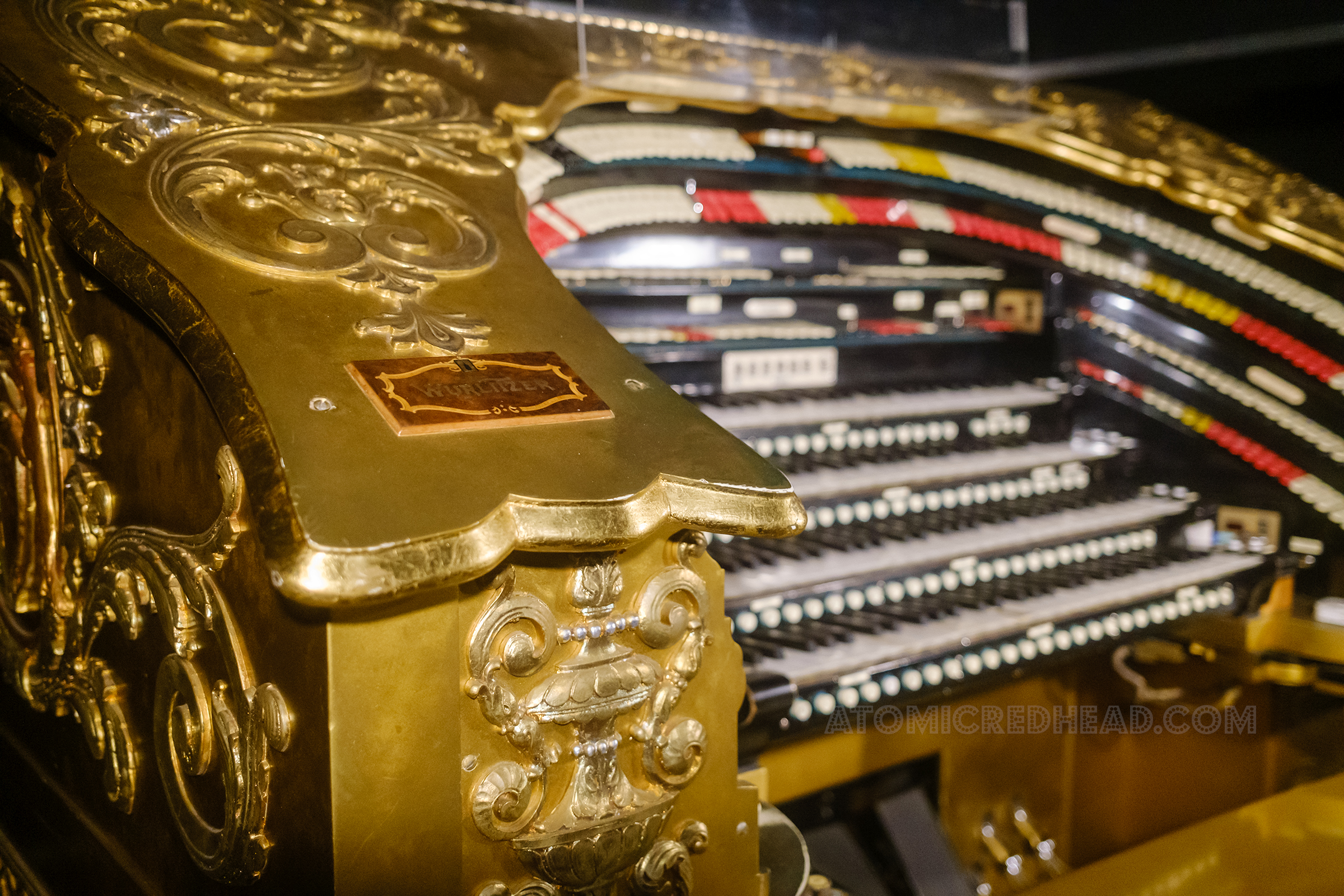 Detail of the edge of the organ, with swirls, curly qs, and a small plaque reading "Wurlitzer"