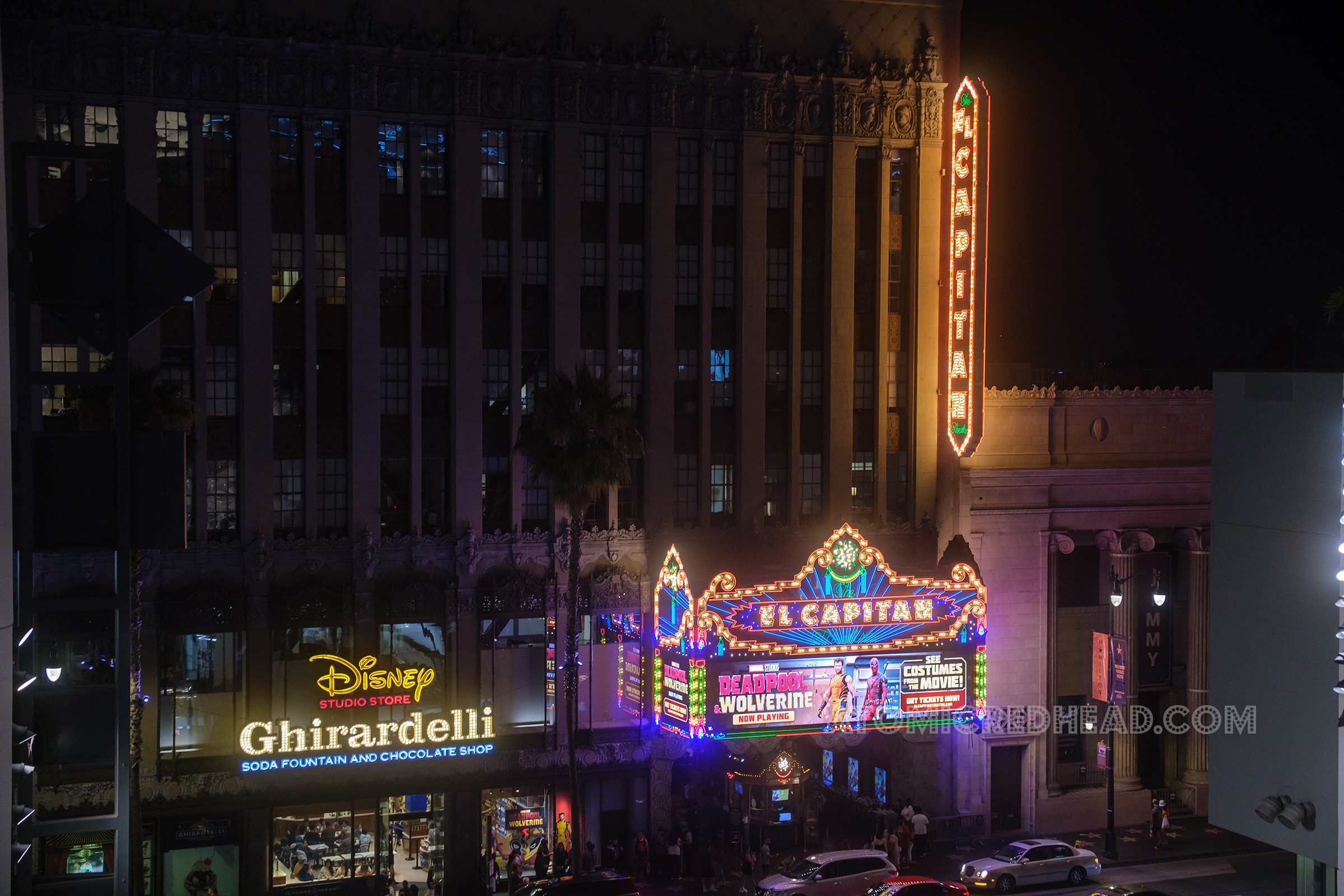 Overall of the El Capitan exterior lit up at night with colorful neon and bulbs.