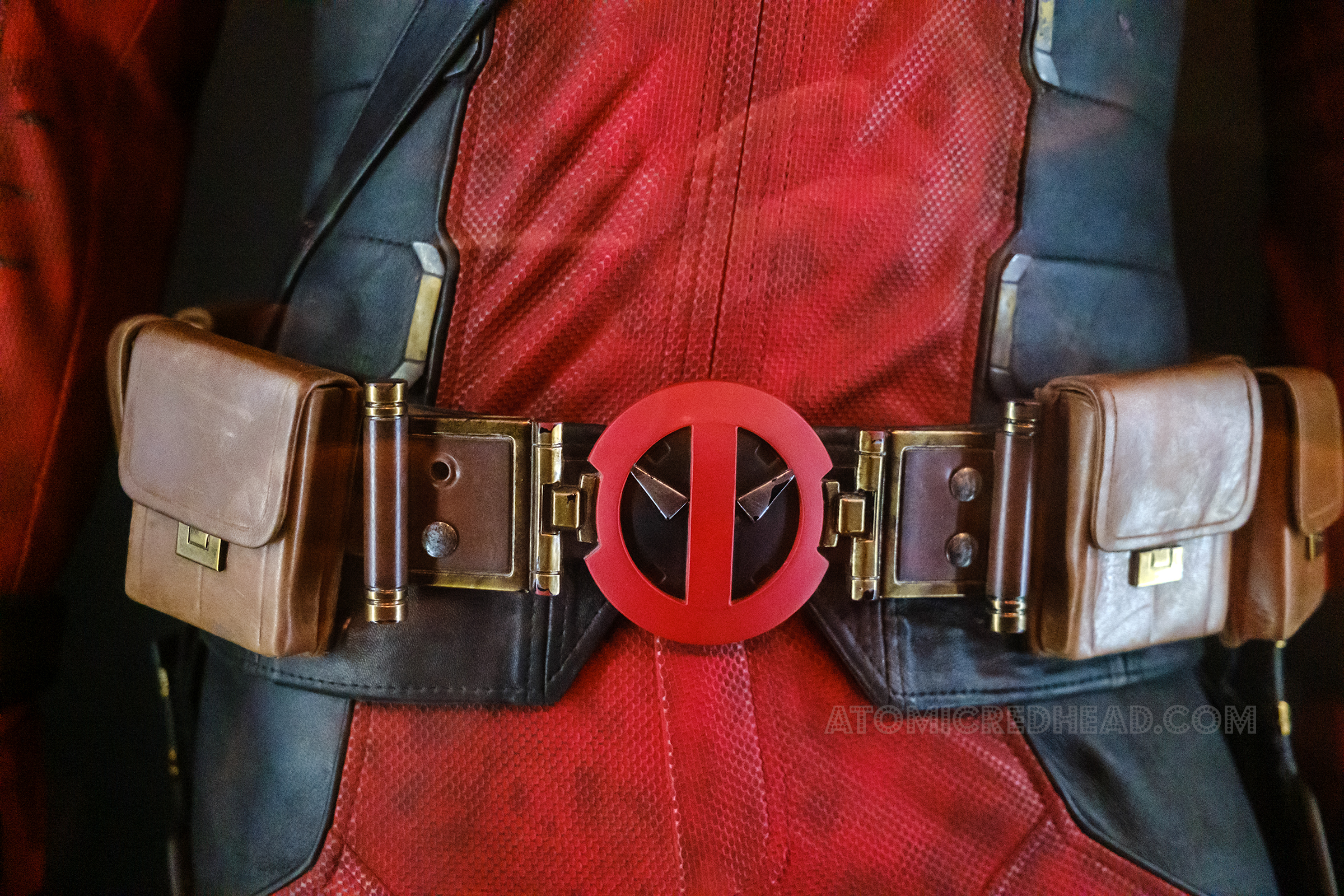 Close-up of Deadpool's belt buckle, that reflects his mask pattern.