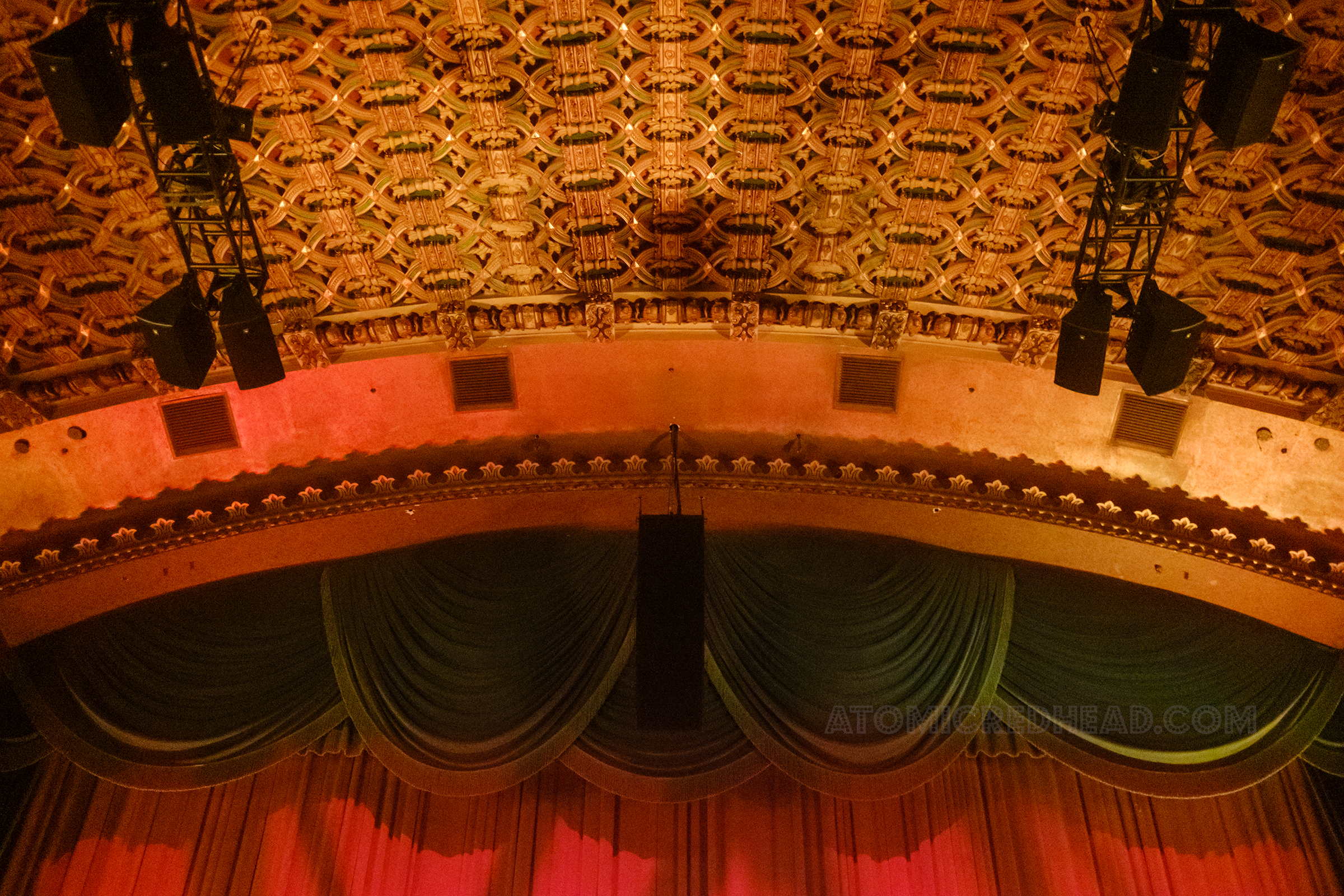 Green curtains hang at the top of the stage, with another curtain behind of red.