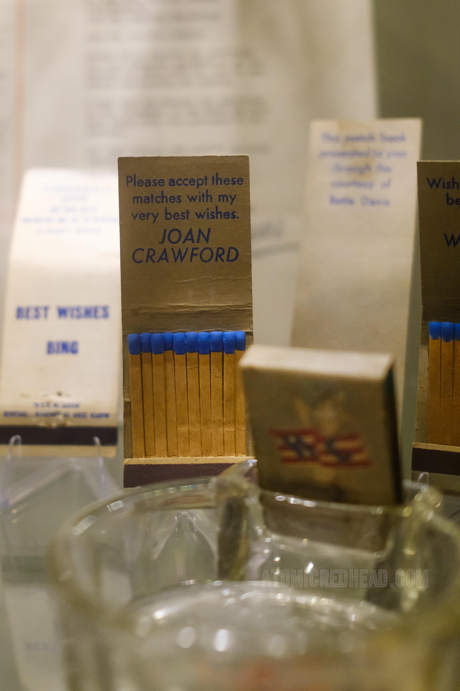 A collection of matchbooks, including an open one that has text reading "Please accept these matches with my very best wishes. Joan Crawford"