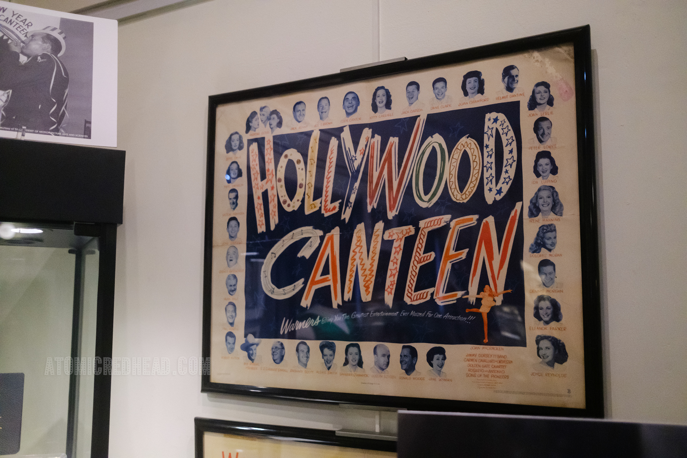 Close-up of a placemat, with reads "Hollywood Canteen" in large red, white, and blue letters and features images of the variety of movie stars that visited.