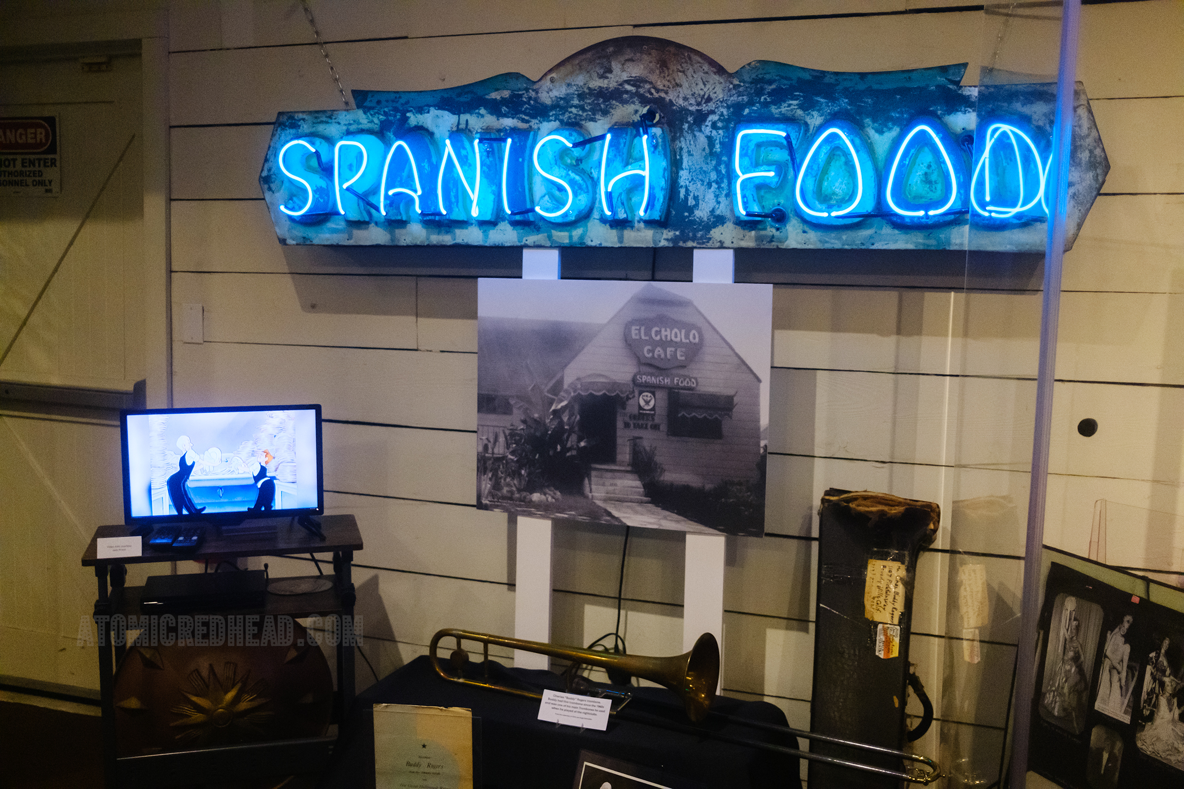 A neon sign reads "Spanish Food" in blue letters. Below a photograph of how it appeared on the restaurant El Cholo