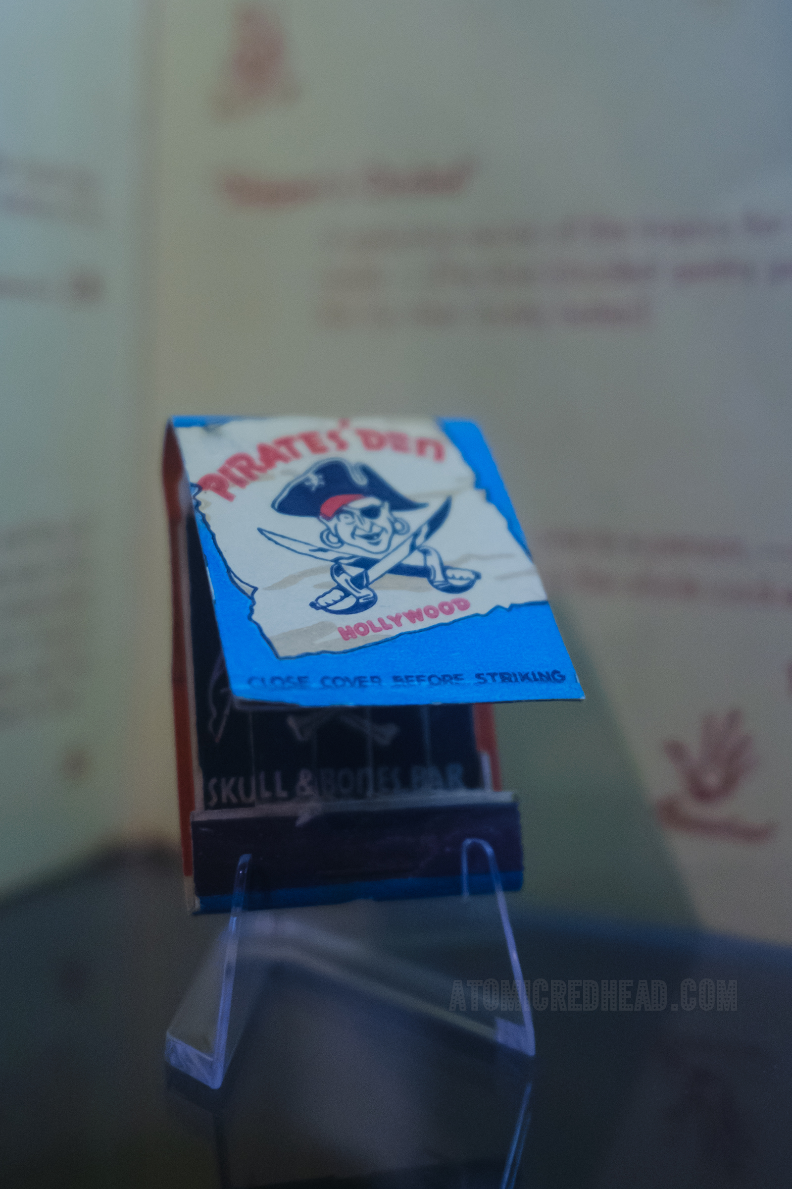A red, white, blue, and black matchbook for The Pirate's Den, featuring a pirate and crossed swords.