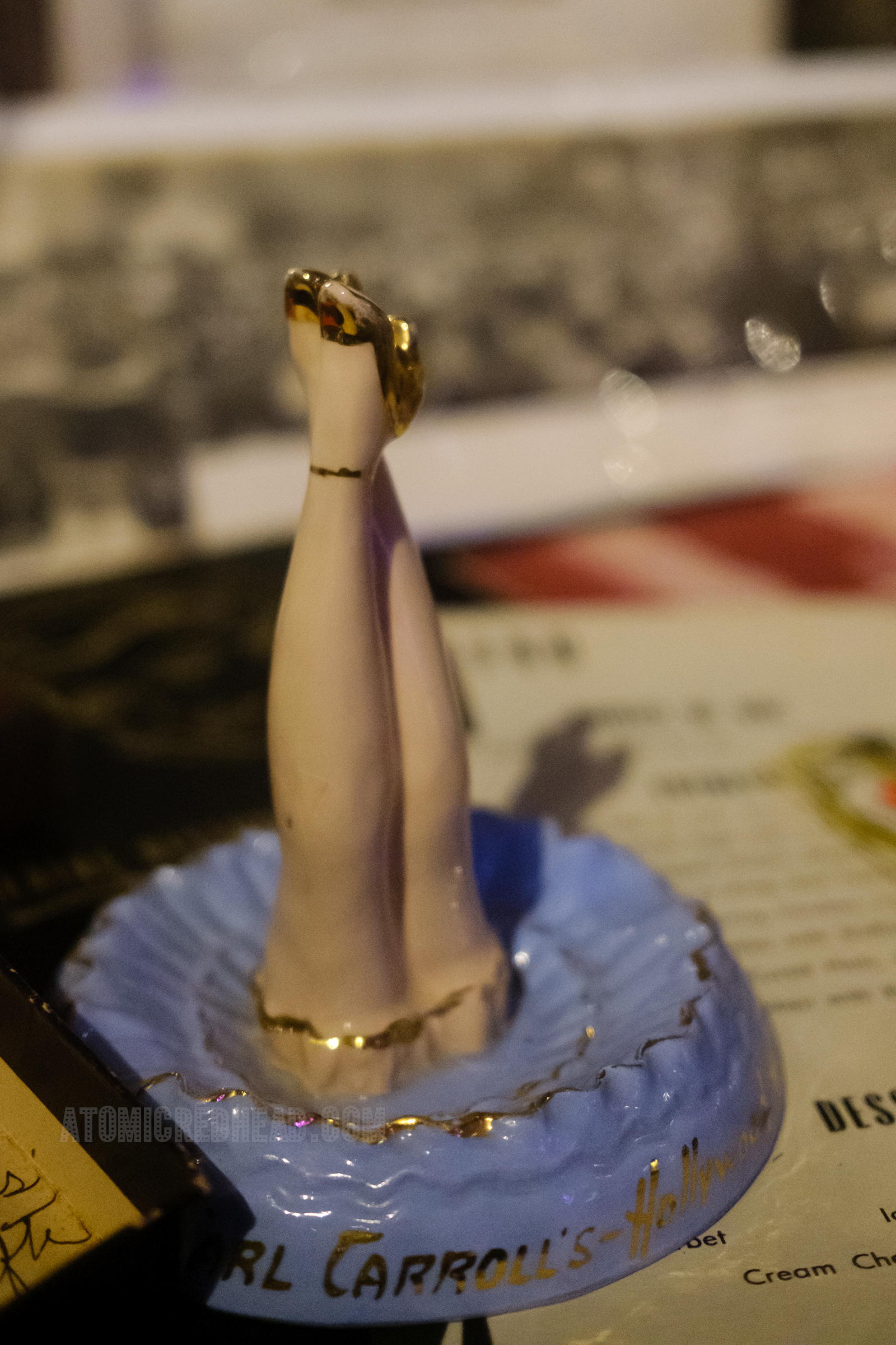 A ceramic dish featuring a woman's legs and gold lettering reading "Earl Carroll Theatre.