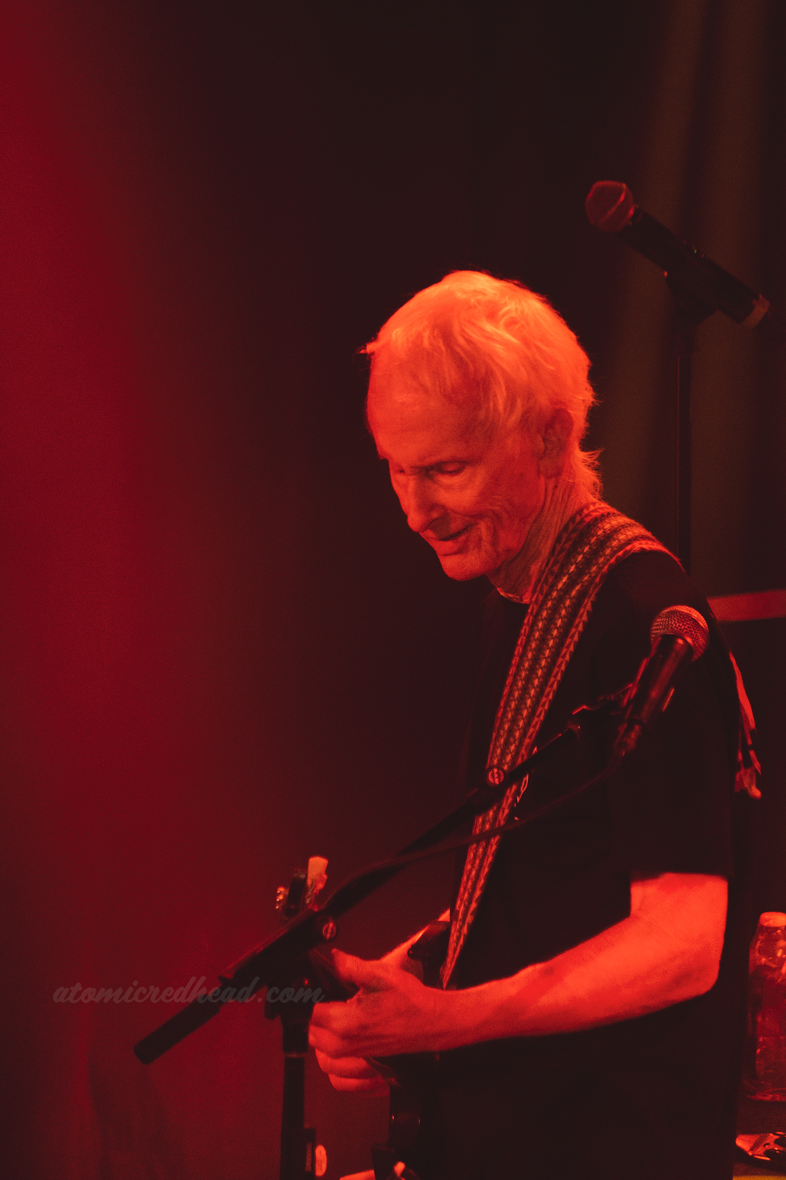 Krieger plays the guitar bathed in red light.