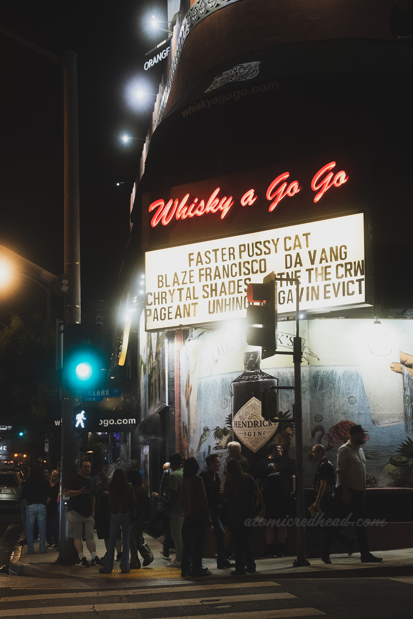 Exterior of the Whisky at night, with the marquee already changed for the next show. People flood the sidewalk and crosswalk exiting the show.