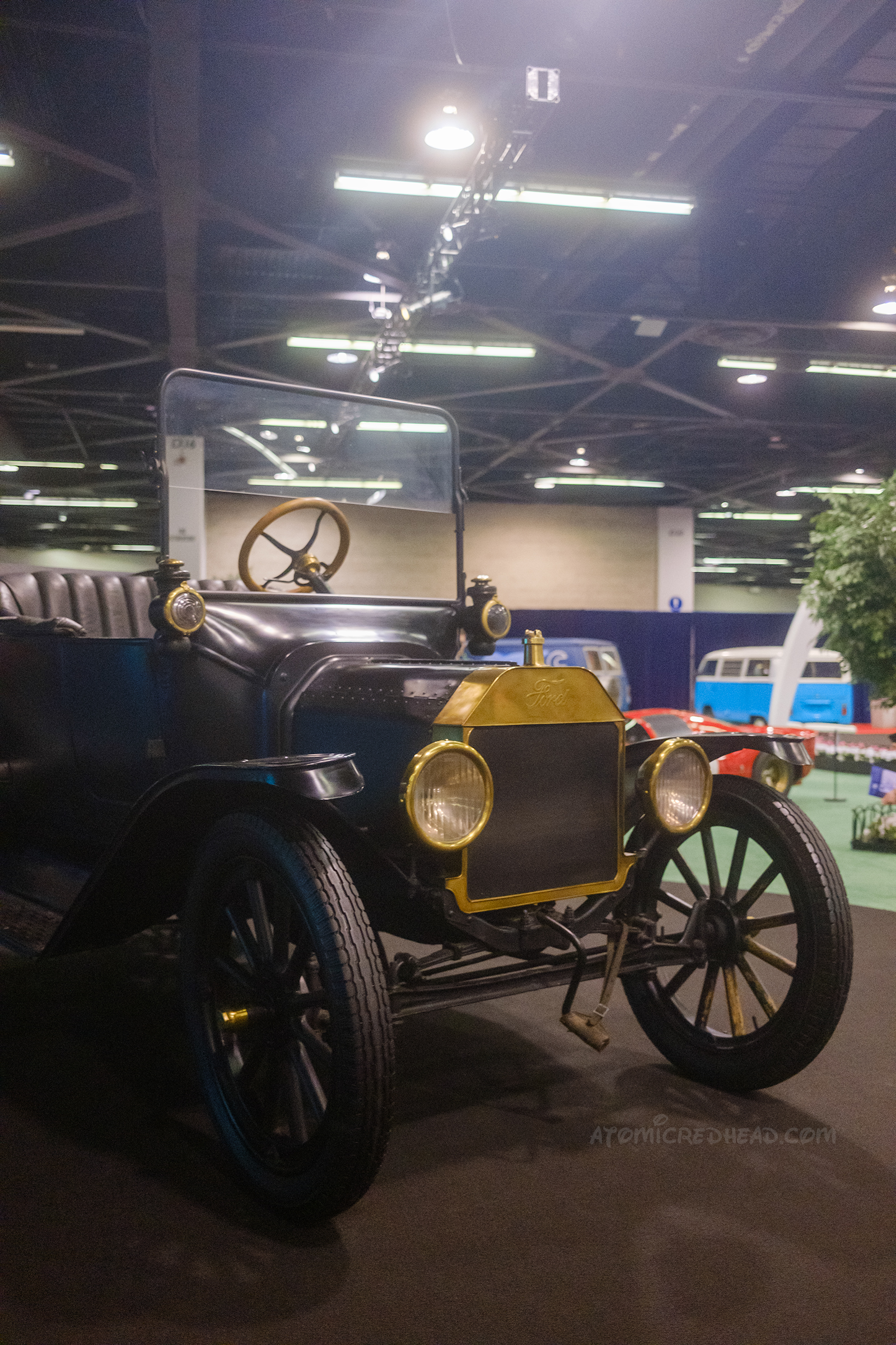 1915 Ford Model T Touring, an open air car with a gold grill, and wire wheels.
