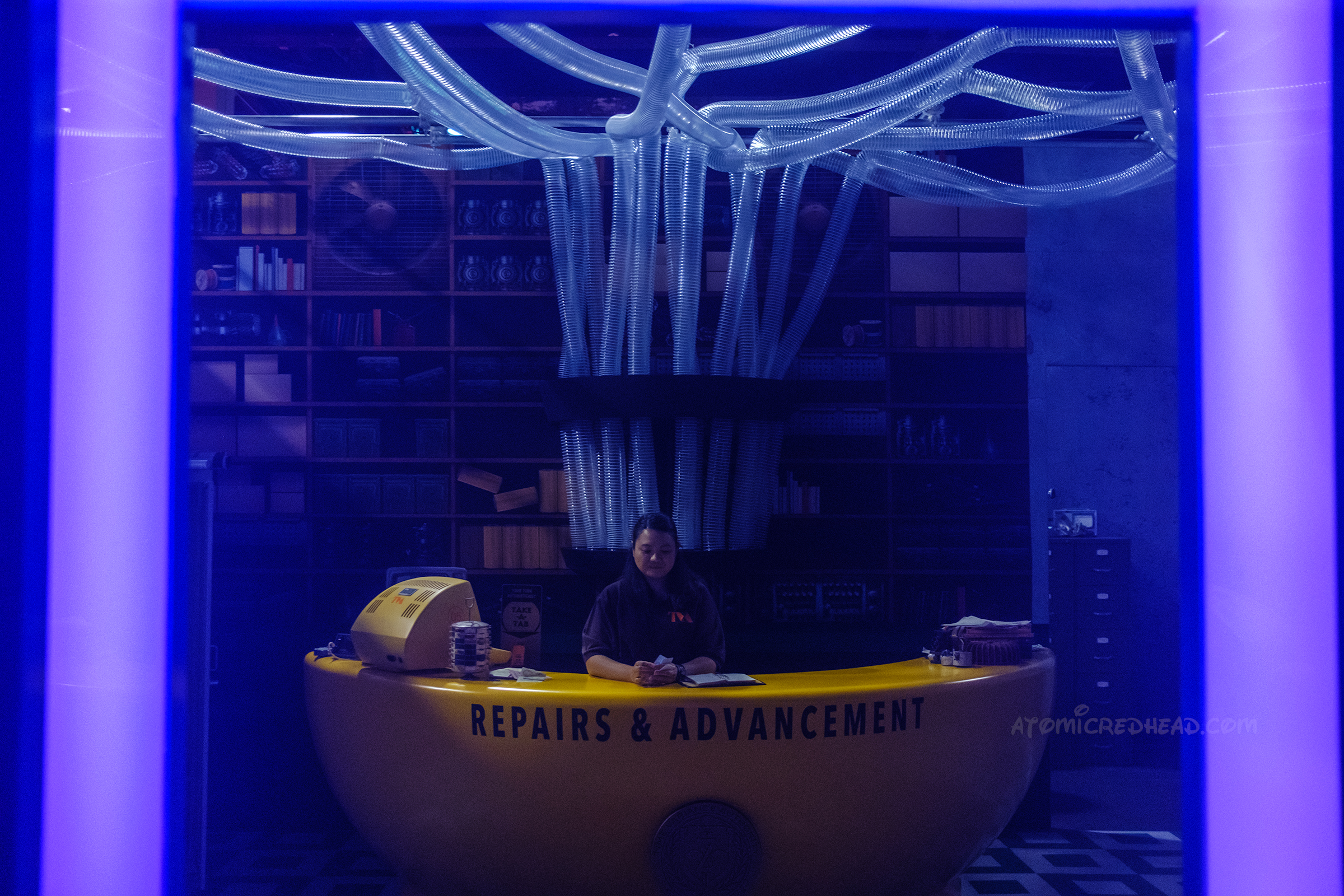 A TVA employee sits at a curved yellow desk with tubes coming down around them.