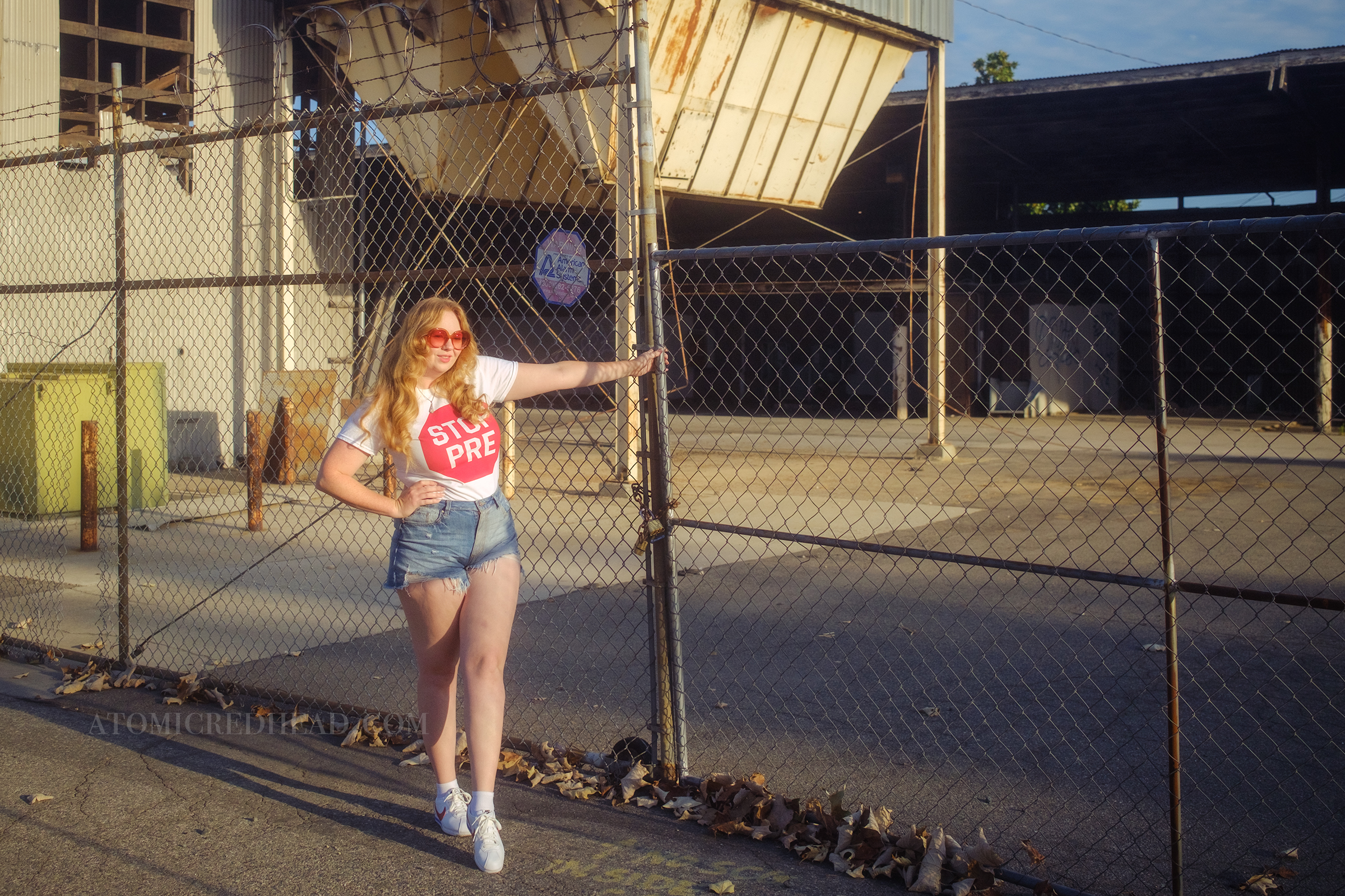 Myself, with my hair down, wearing a white tshirt featuring a red stop sign reading "Stop Pre" blue jean cut off shirts, and red, white, and blue Nike shoes.