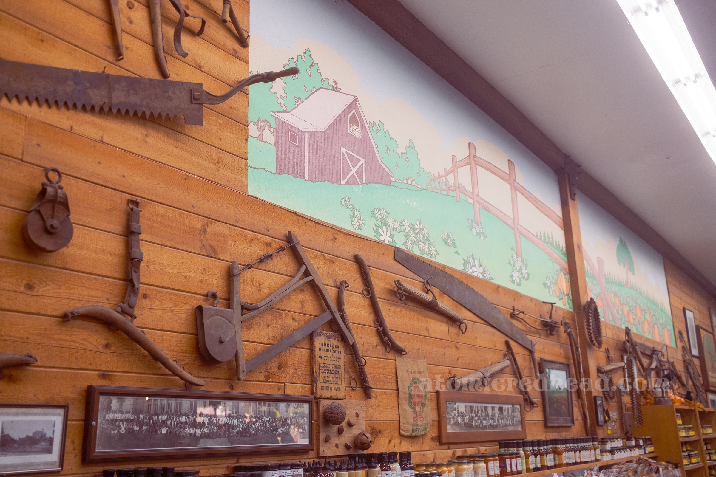 Antique farm equipment hangs on the wall of the shop, and painted on a portion is a mural of a farm with a barn.