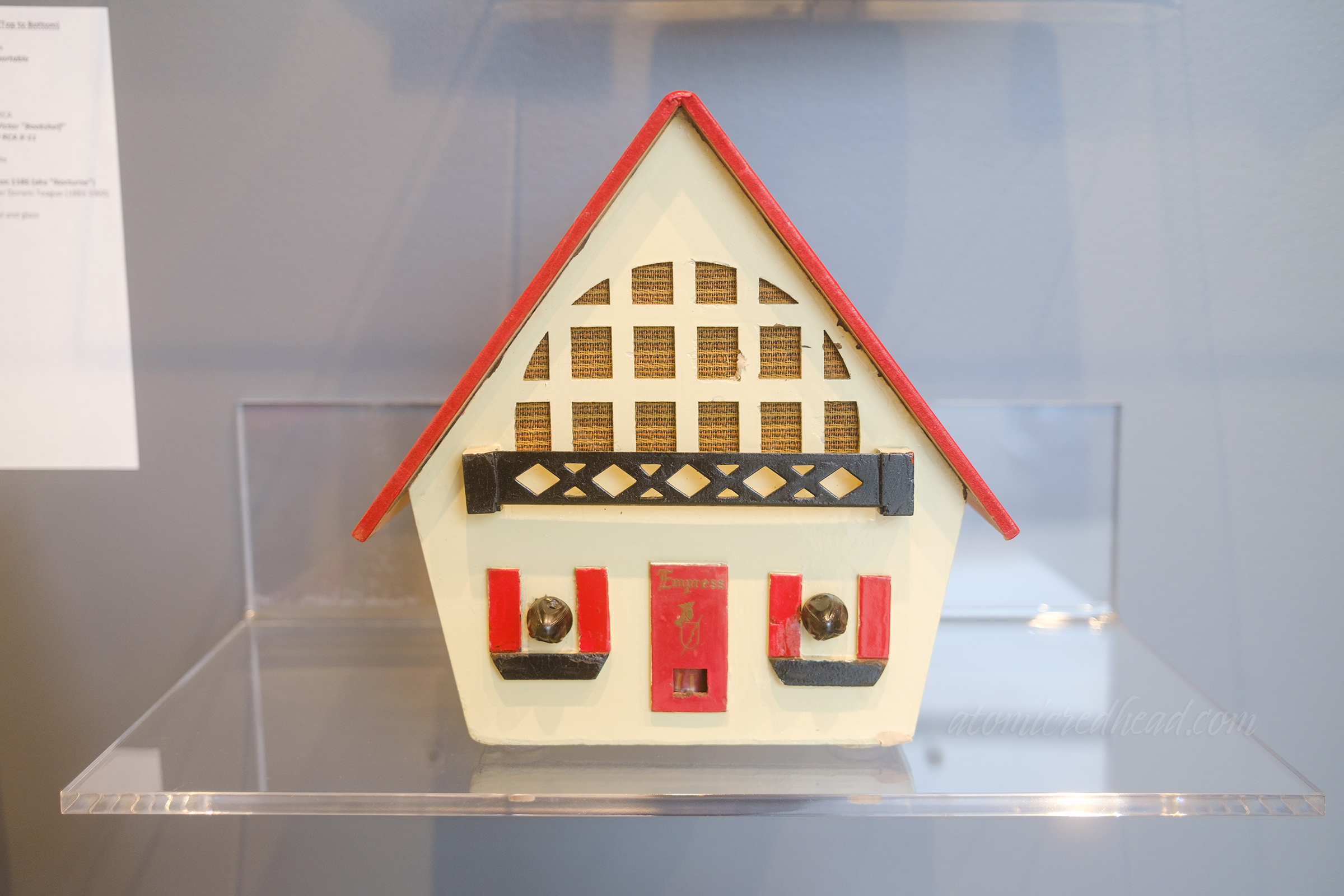 A radio shaped light a house, white with a red roof and red shutters.