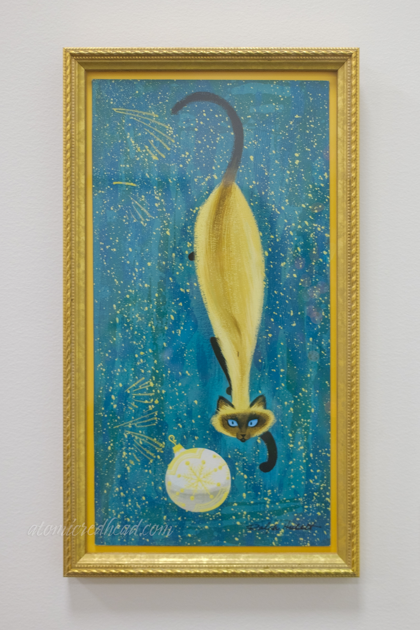 A Siamese cat eyes a white ornament.