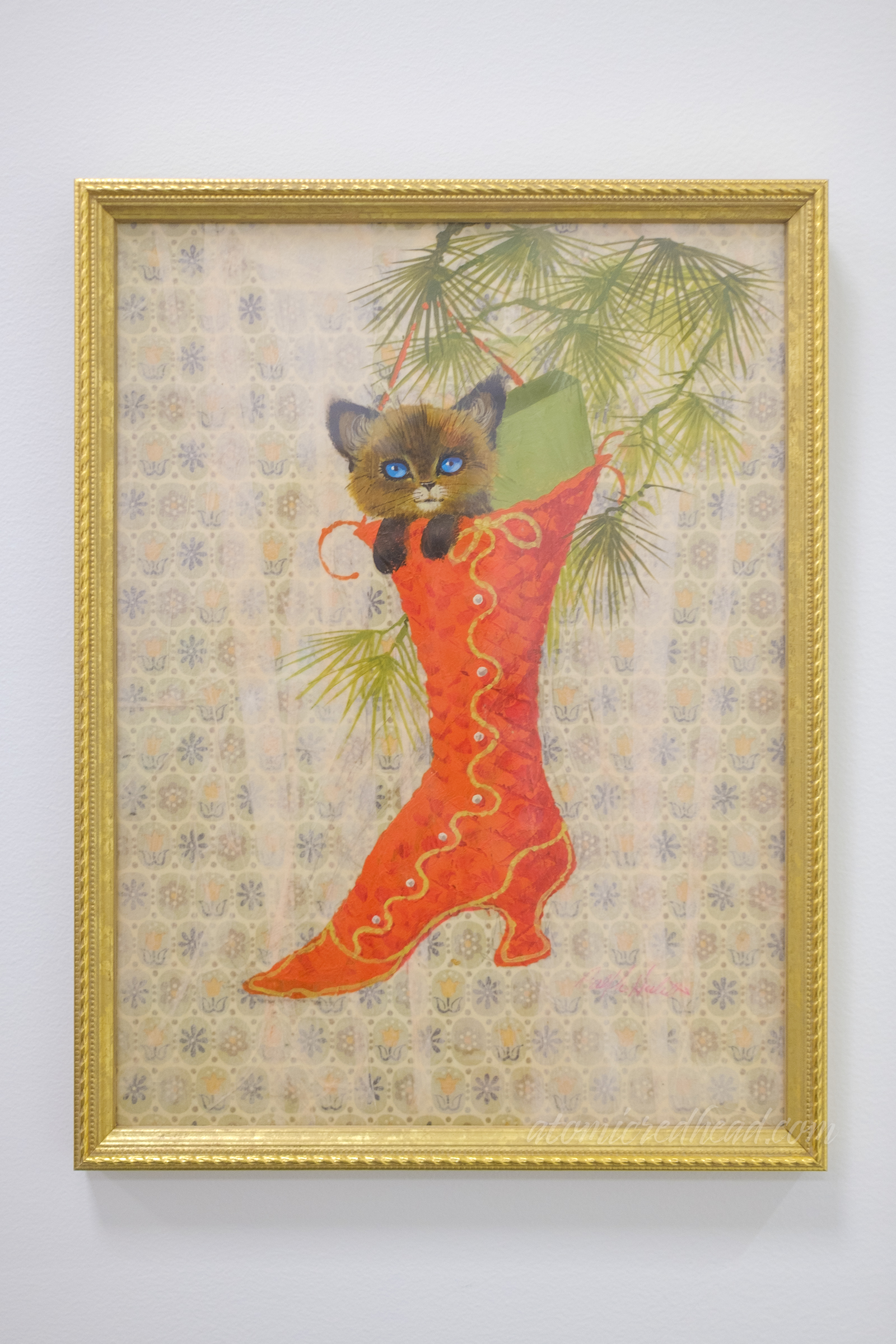 A Siamese cat peeks out of a stocking shaped like a Victorian boot.