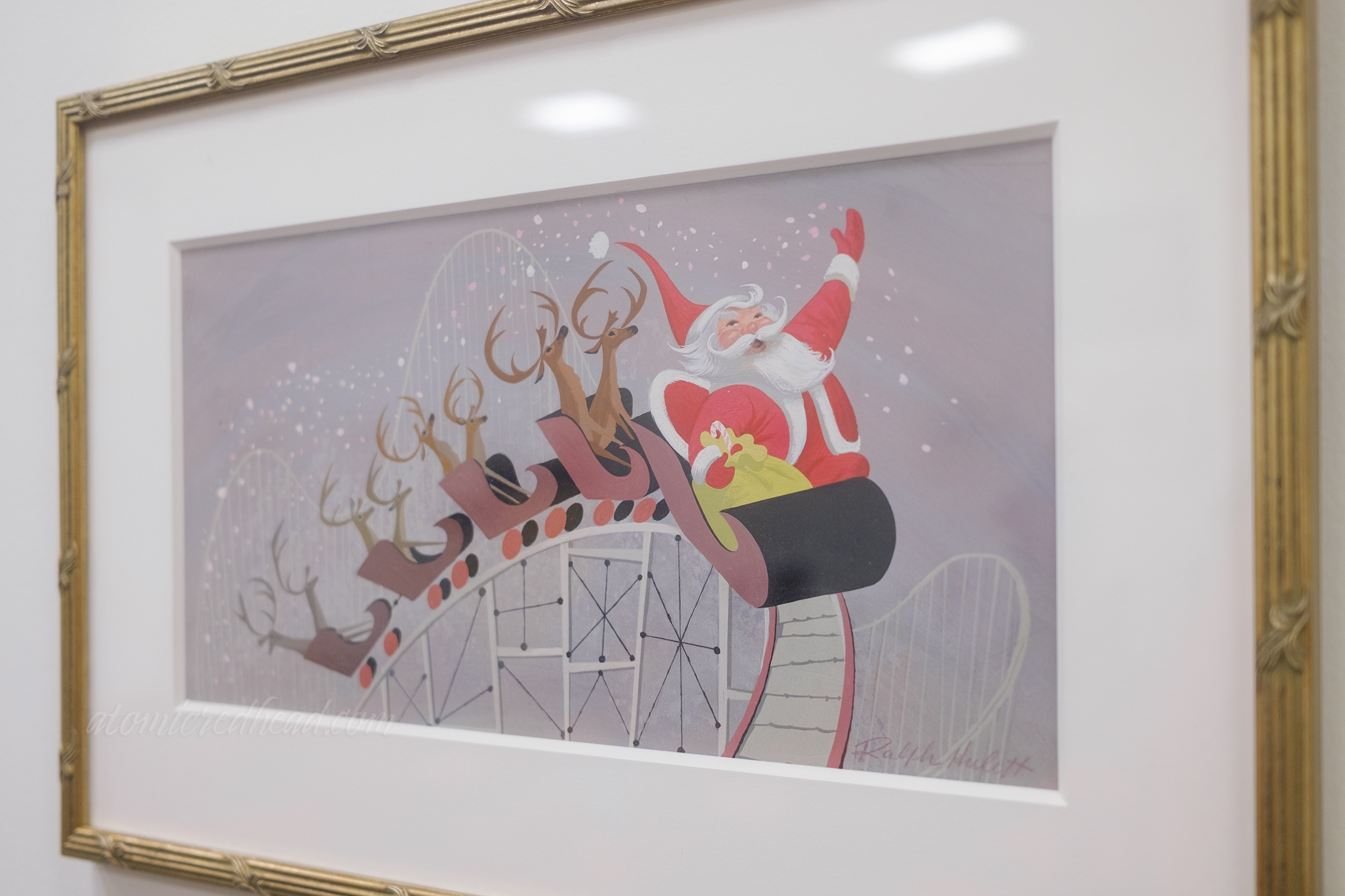 Santa rides in the front of a roller coaster with his reindeer behind.