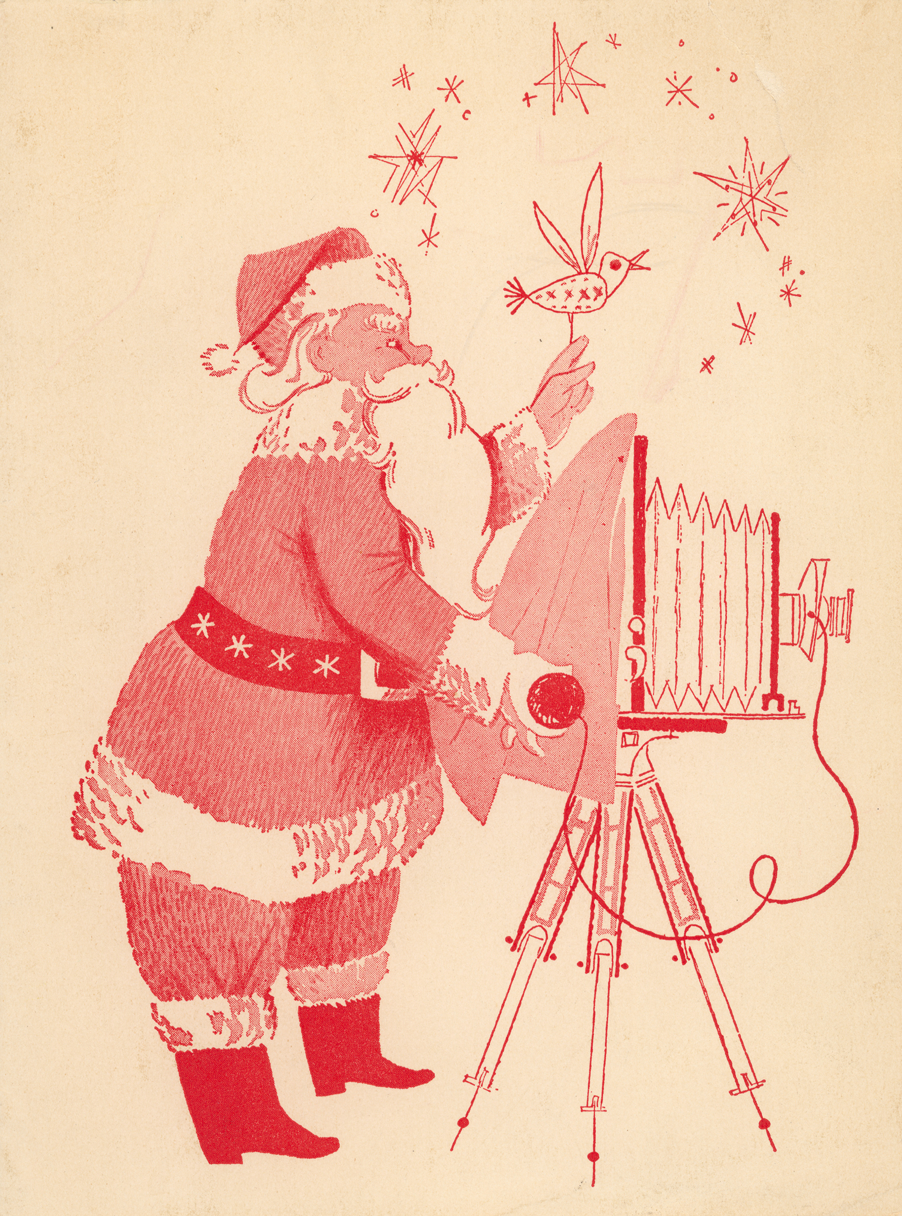 Santa stands behind a camera holding a bird.