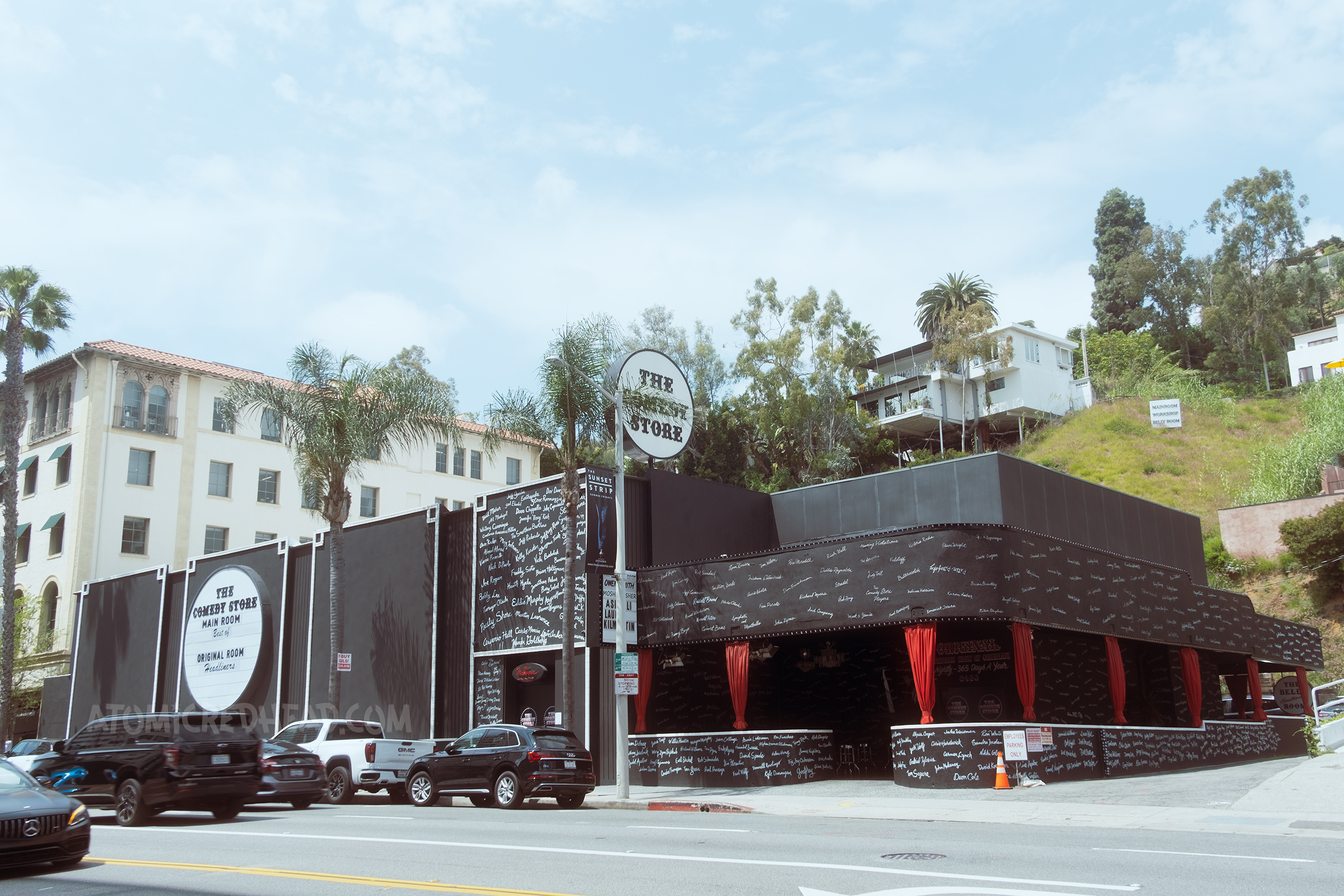 Exterior of The Comedy Store, a black building with signatures of various comedians in white on front.