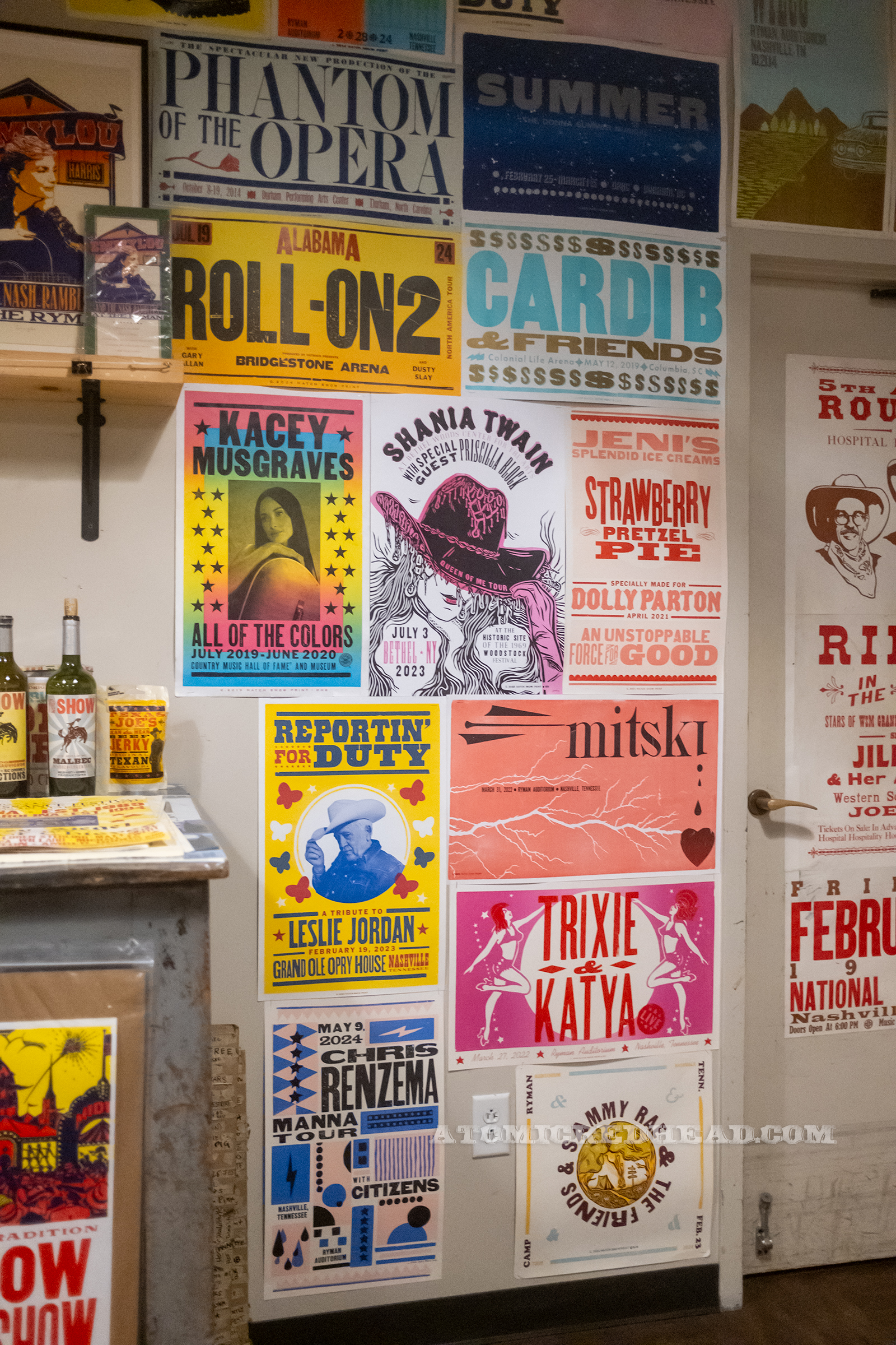 A portion of the classroom wall covered in posters, some of which are for Shania Twain, Kasey Musgraves, and Trixie & Katya.