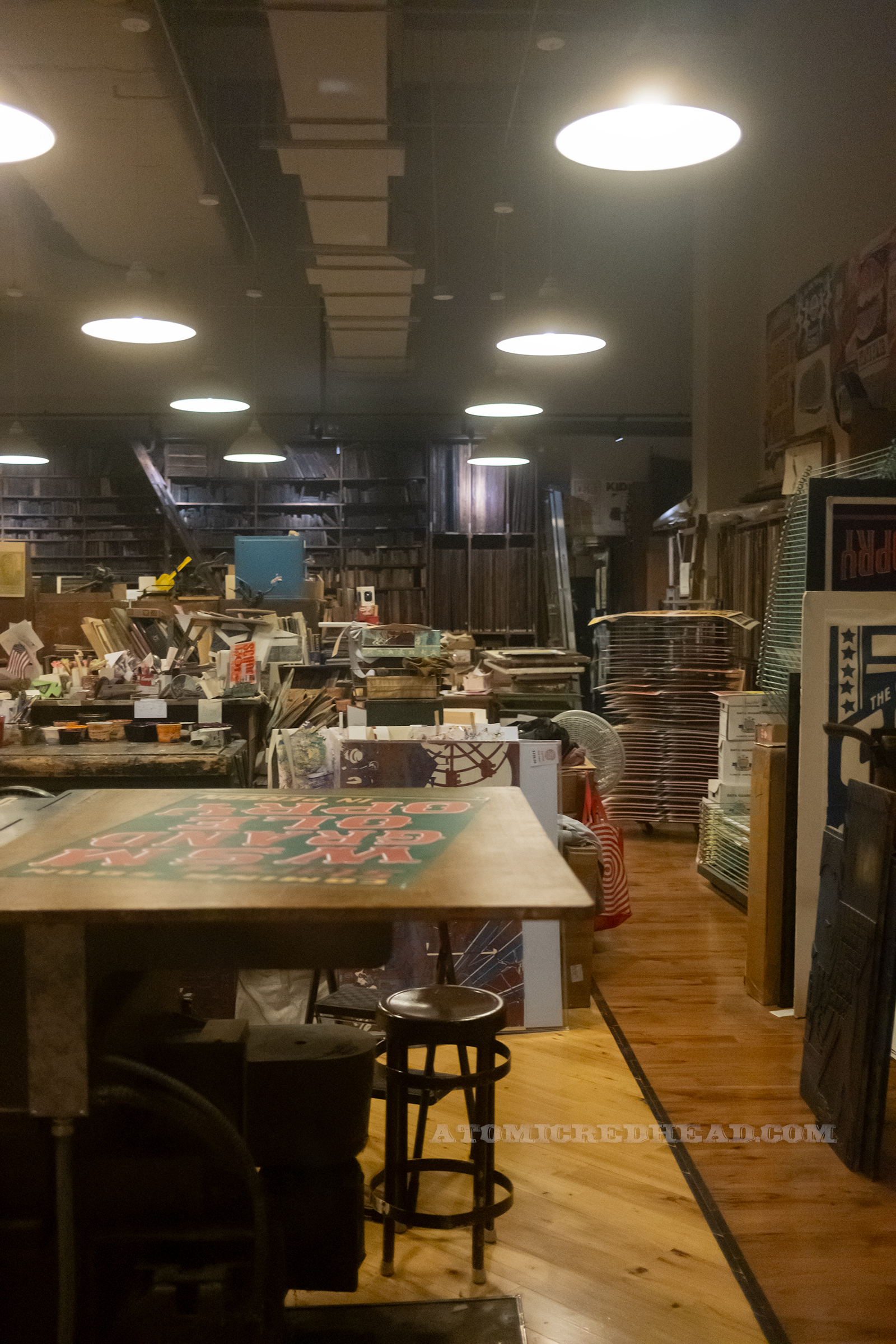 Portion of the workshop with the shelves of blocks in the back and desks.