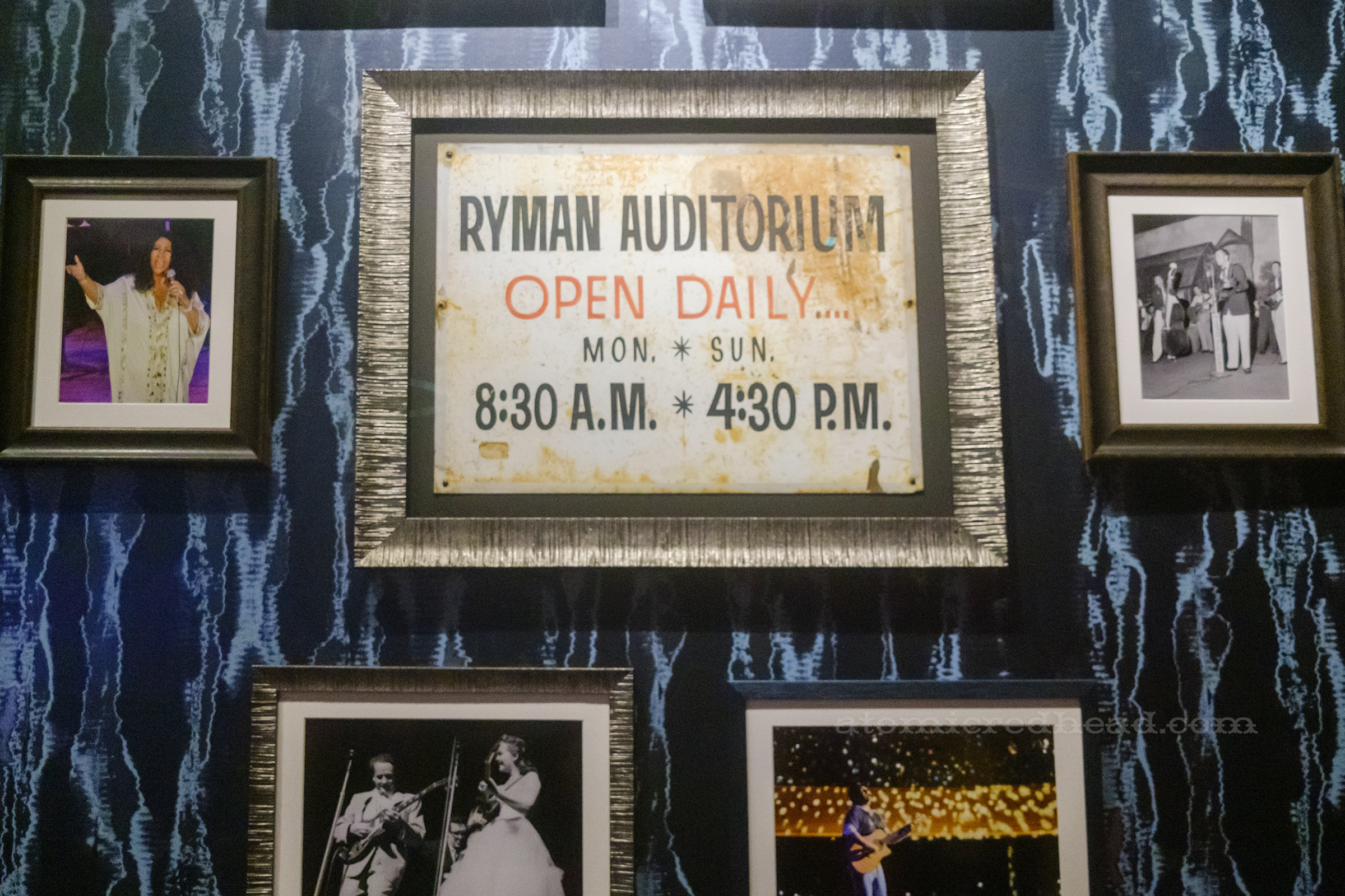 A vintage framed sign that reads "Ryman Auditorium Open Daily Mon-Sun 8:30 am-4:30 pm"