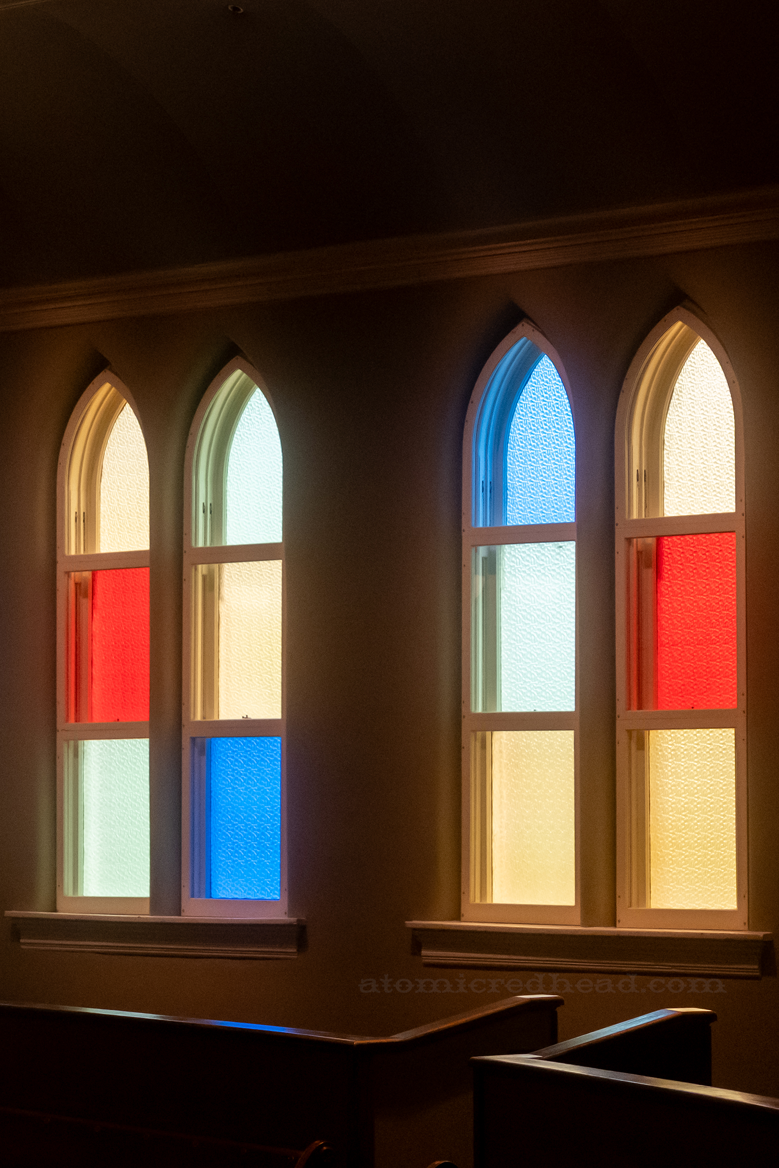Close-up of the arched windows of red, yellow, blue, and green stained glass.
