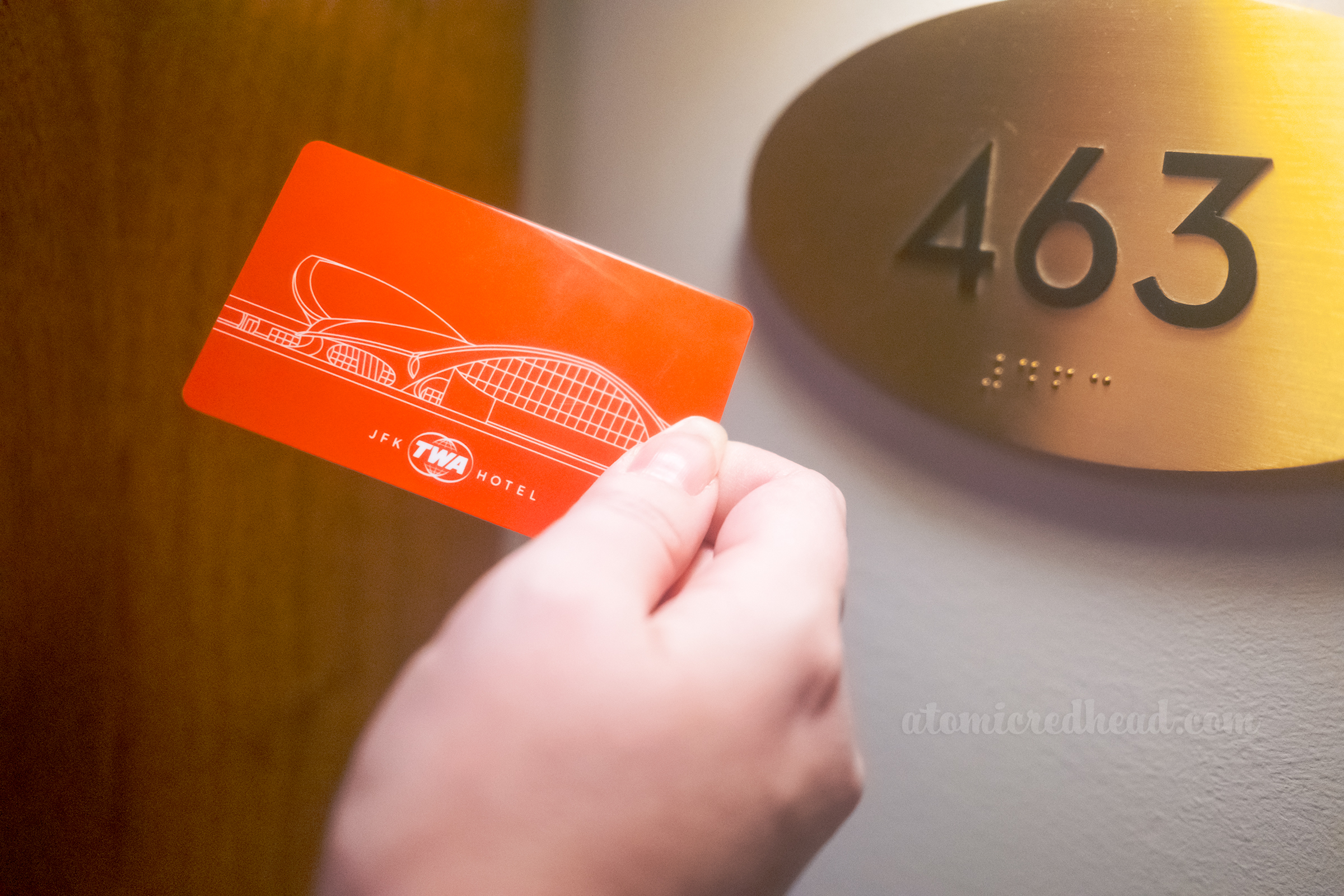 Close-up of the hotel room key card, a red card with a line illustration of the exterior of the building, behind is the oval gold room number reading "463"