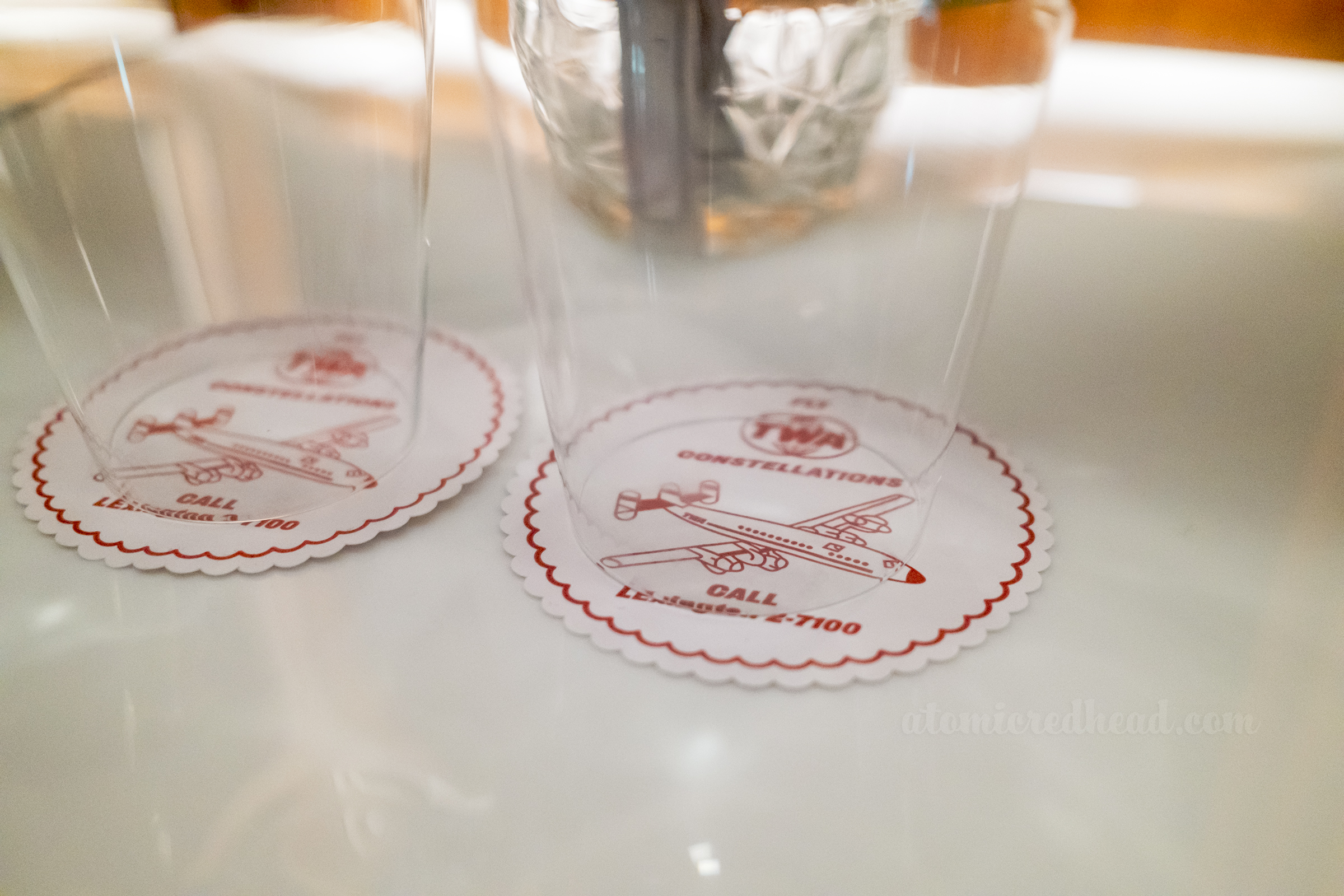 Close-up of glasses on coasters that have an image of the Connie plane on them.