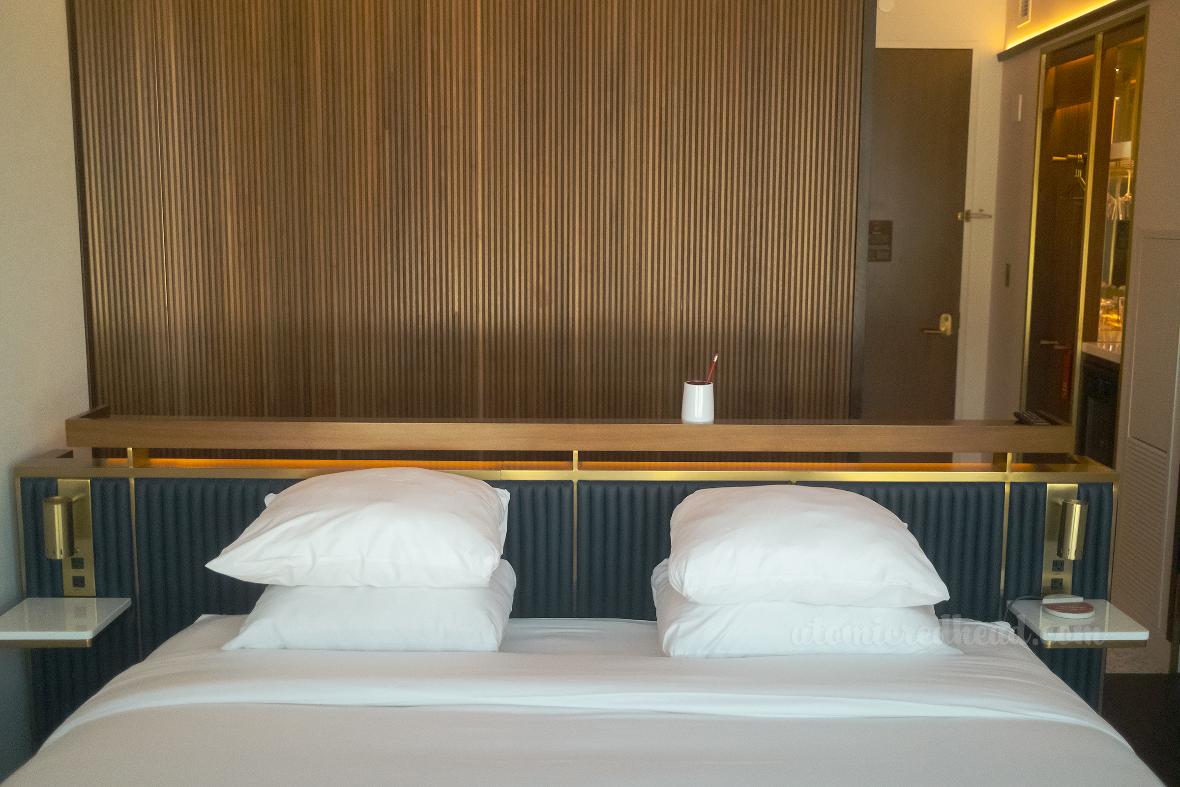 Overview of the king size bed, in the background a dark wood wall.