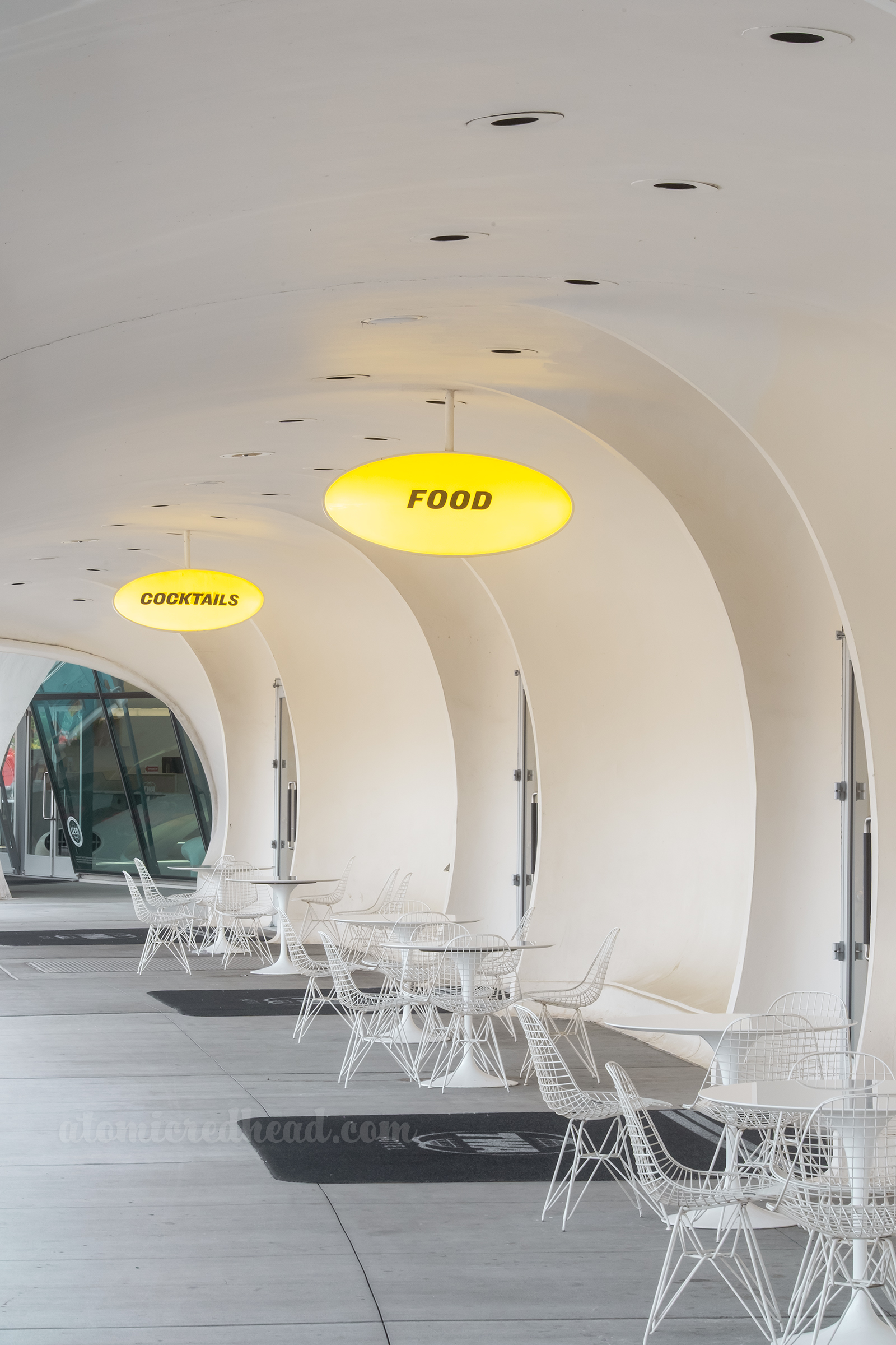 A curved arcade has tables out front.