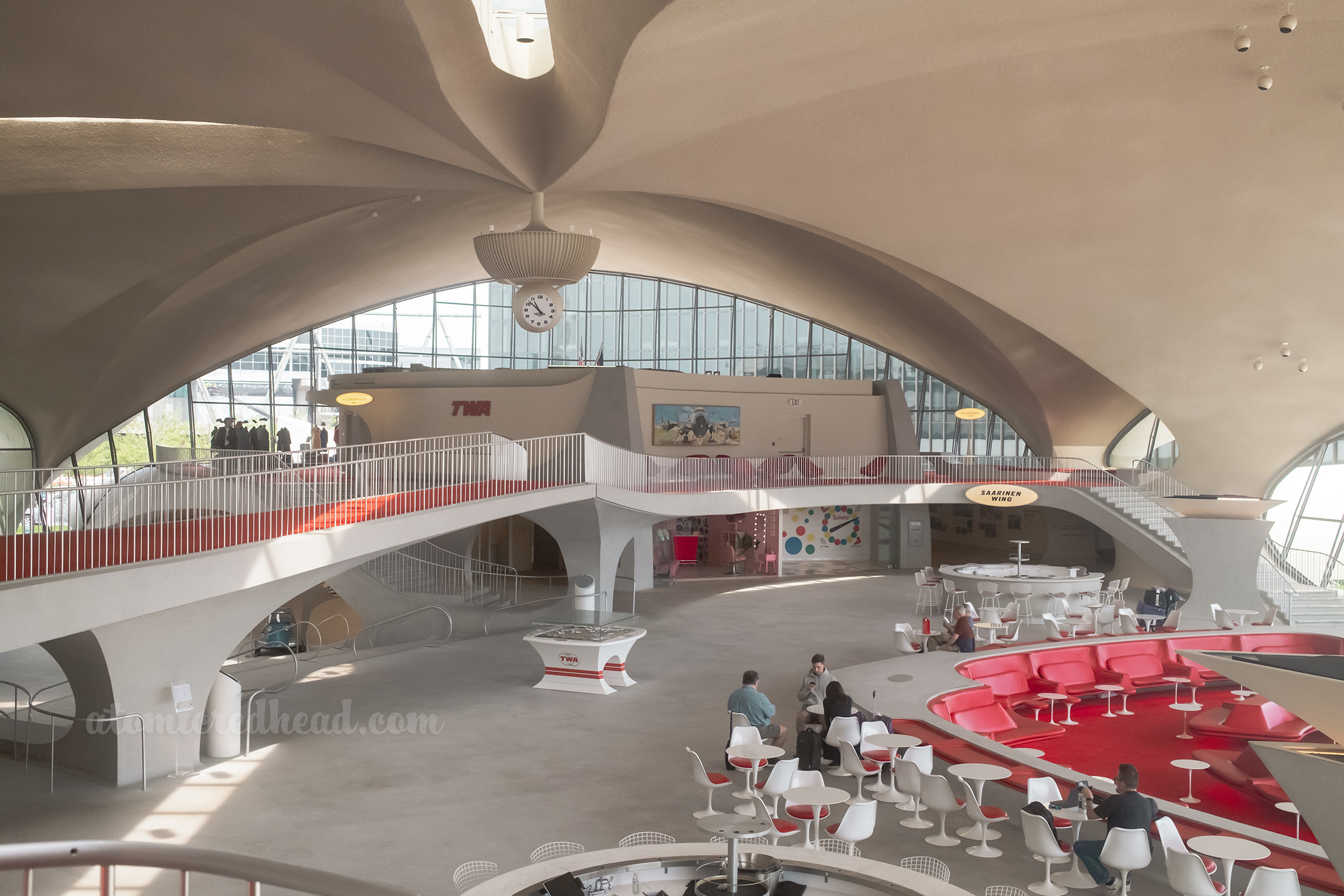 Overall of part of the lobby, on the right is the sunken lounge with red seats, a bridge crosses across the left with red carpet.