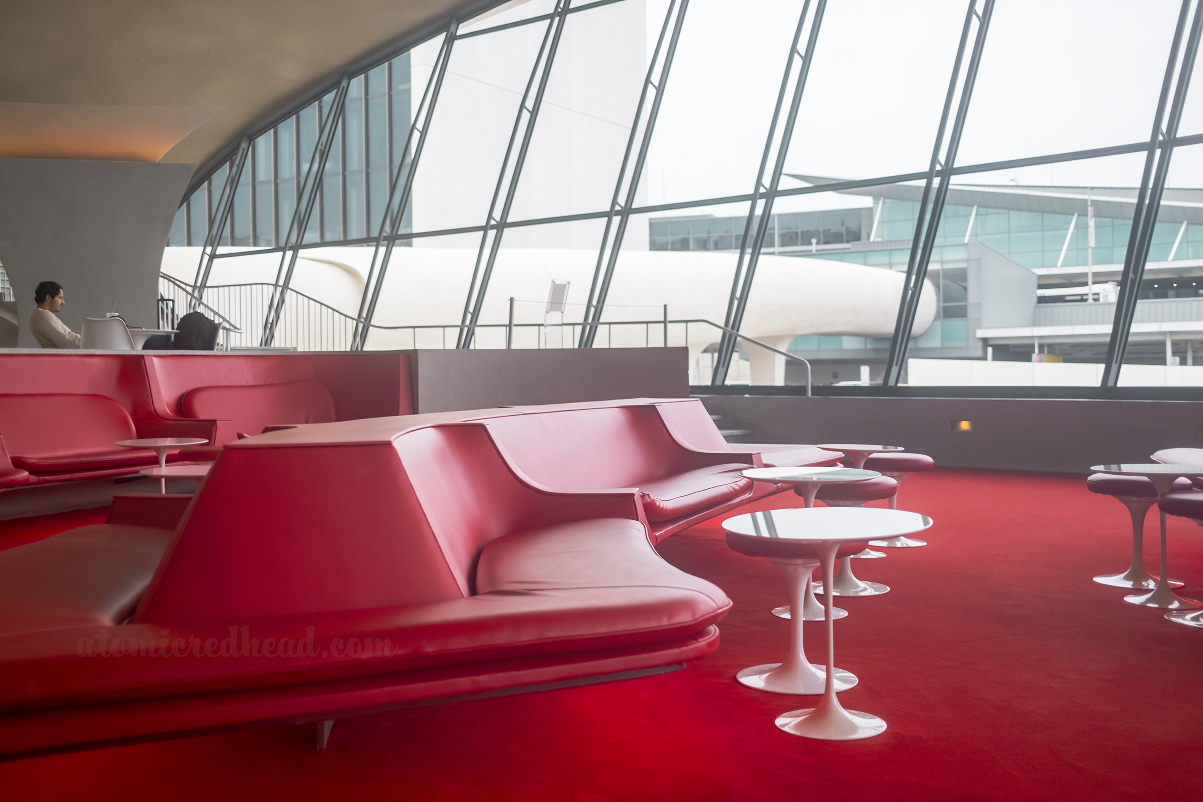 View of the sunken lounge with the tube hallways that connect to the active terminal in the background through the expansive window.