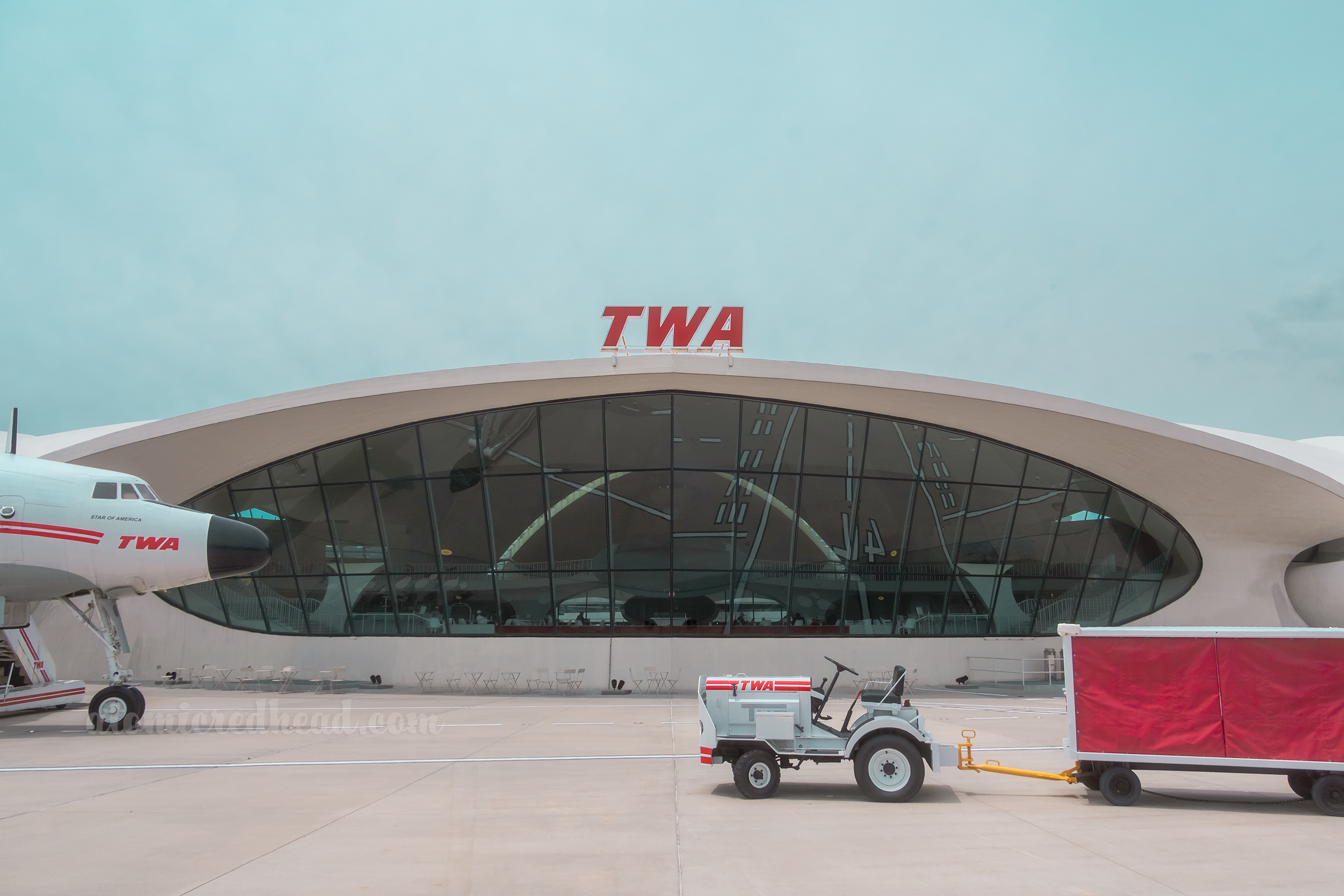 View of the exterior back with a massive window and an old luggage trolly.