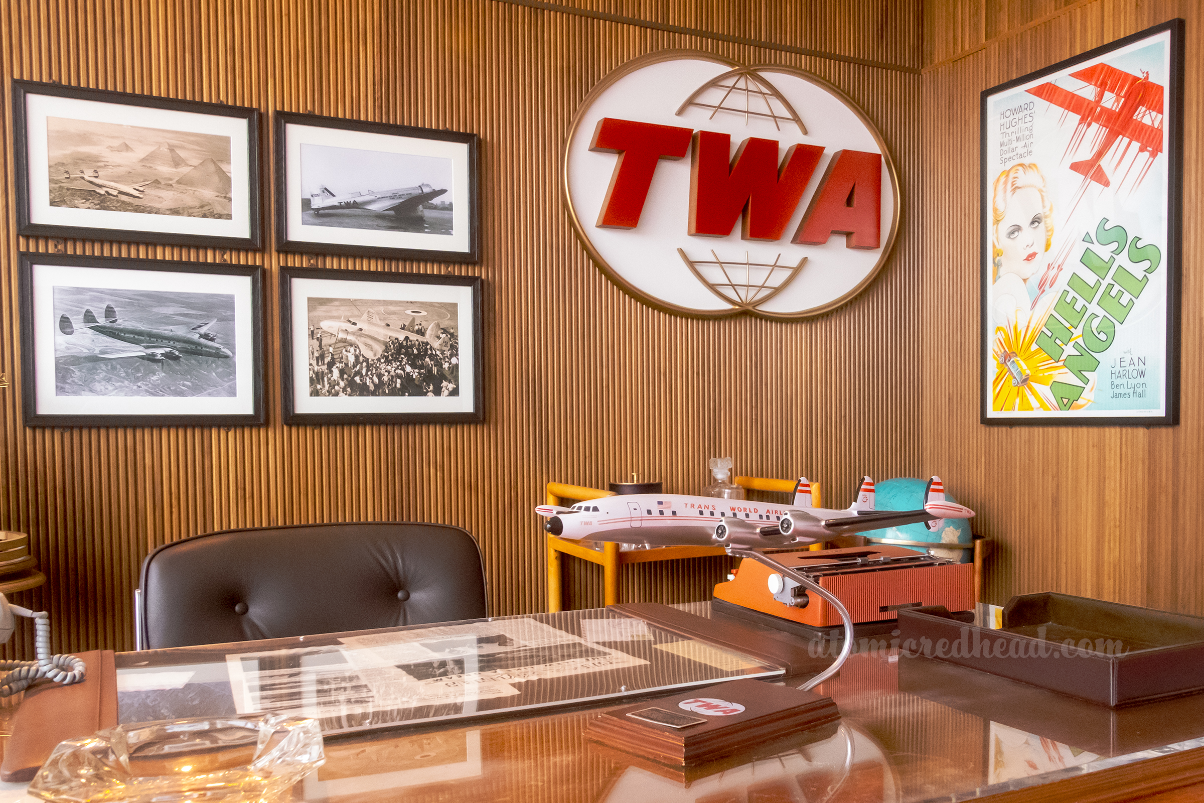 A mock-up of Howard Hughs' old office, with wood panel walls, the TWA logo, and a model plane on the desk.