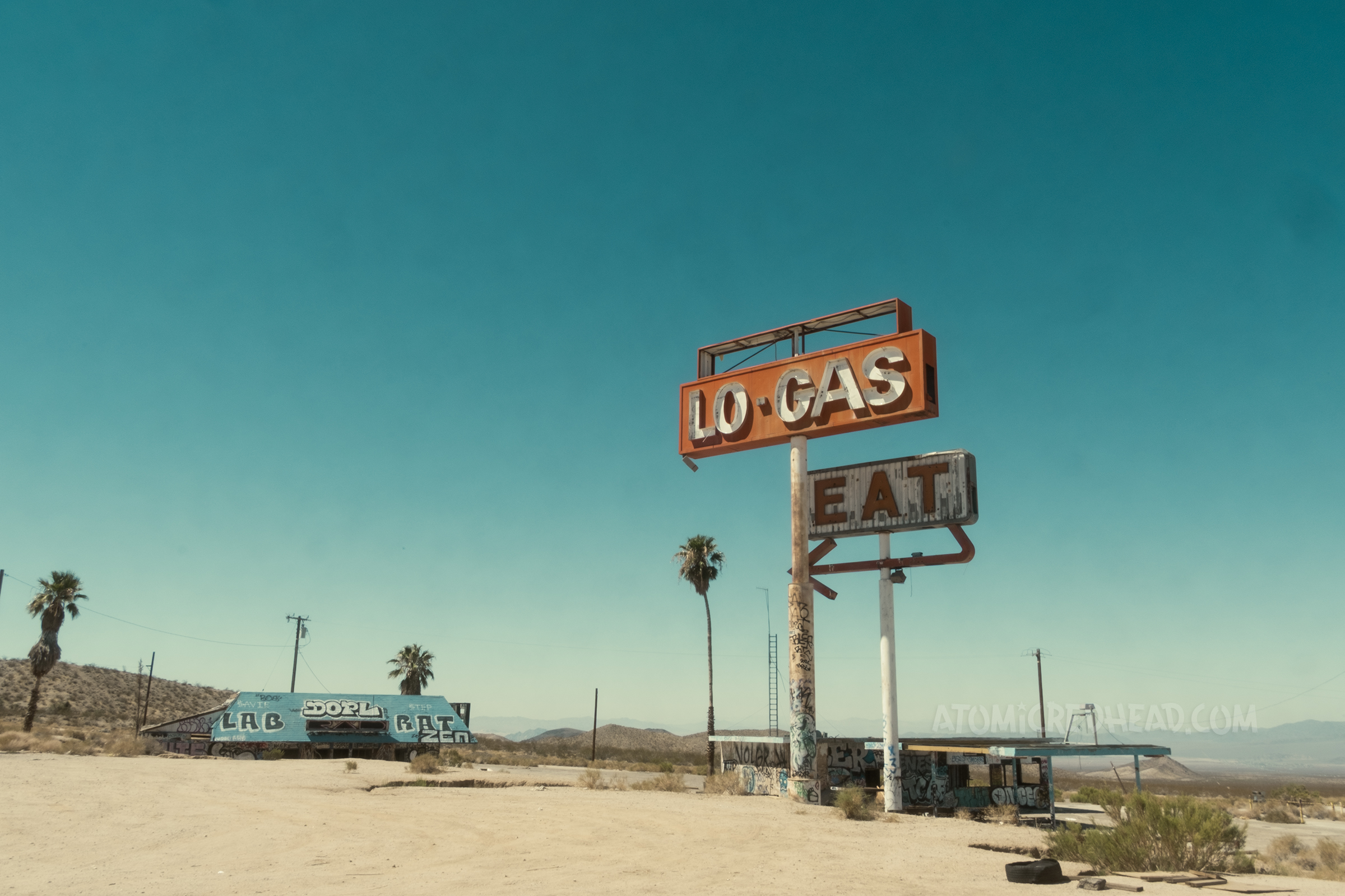 Overall view of the Hi-Low restaurant and gas station, with the restaurant on the left, and the gas station on the right. The signs reading "Lo-Gas" and "Eat" tower in the middle.