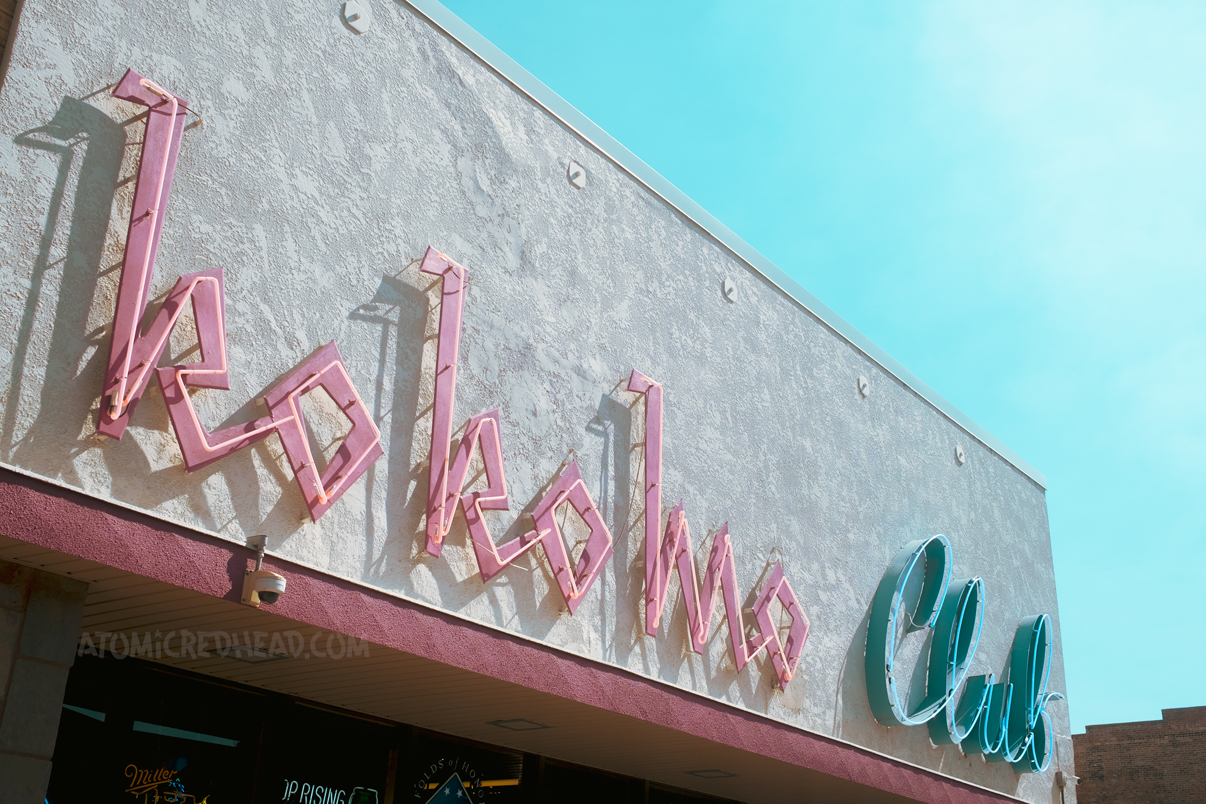 Red and blue neon on a building reads "Ko Ko Mo Club"