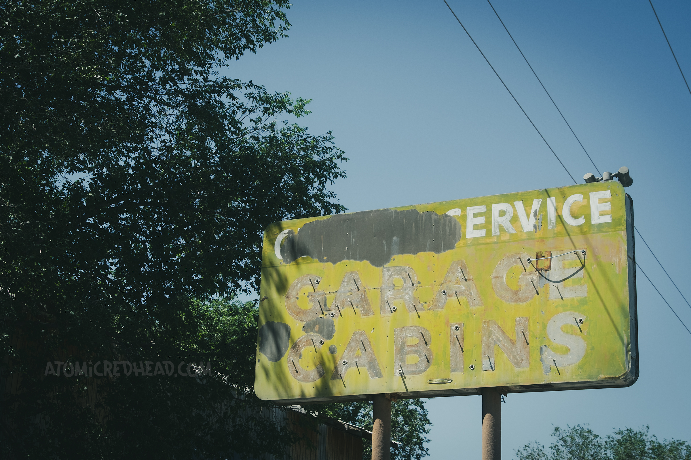A faded and flaking metal sign reads "Garage Cabins" in green and white.