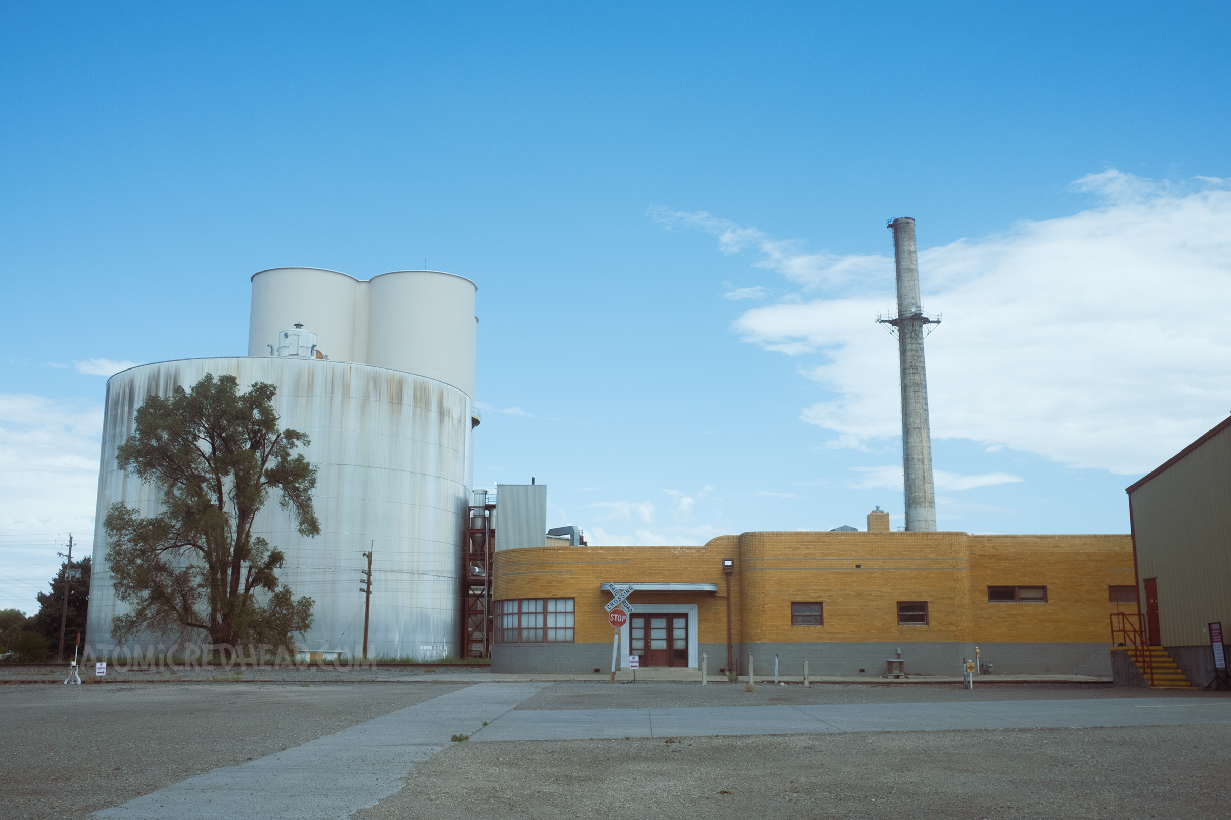 A beautiful yellow prick Streamline Moderne building with curved lines sits near the railroad tracks.
