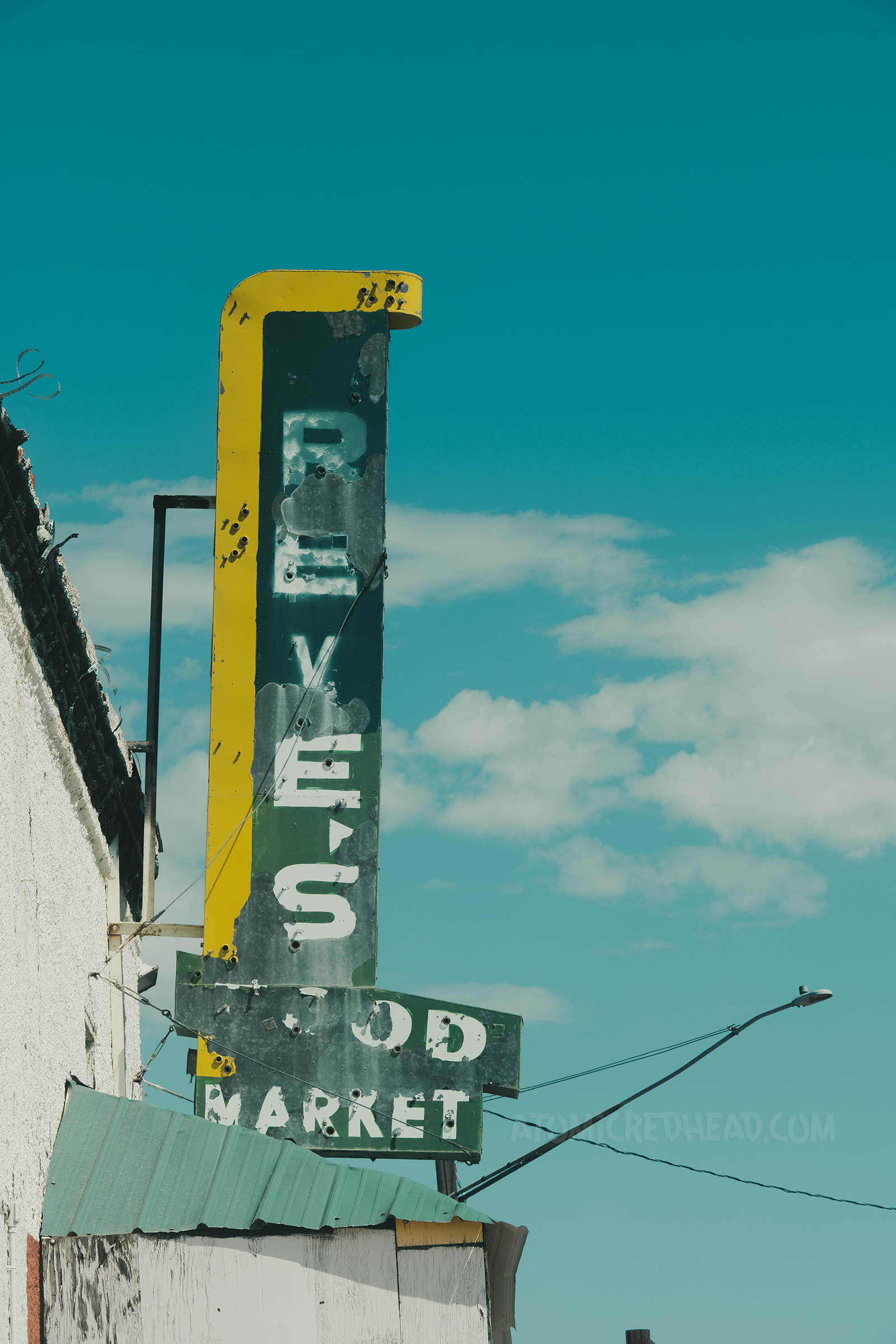 A flaking green and yellow blade style neon sign for a market.