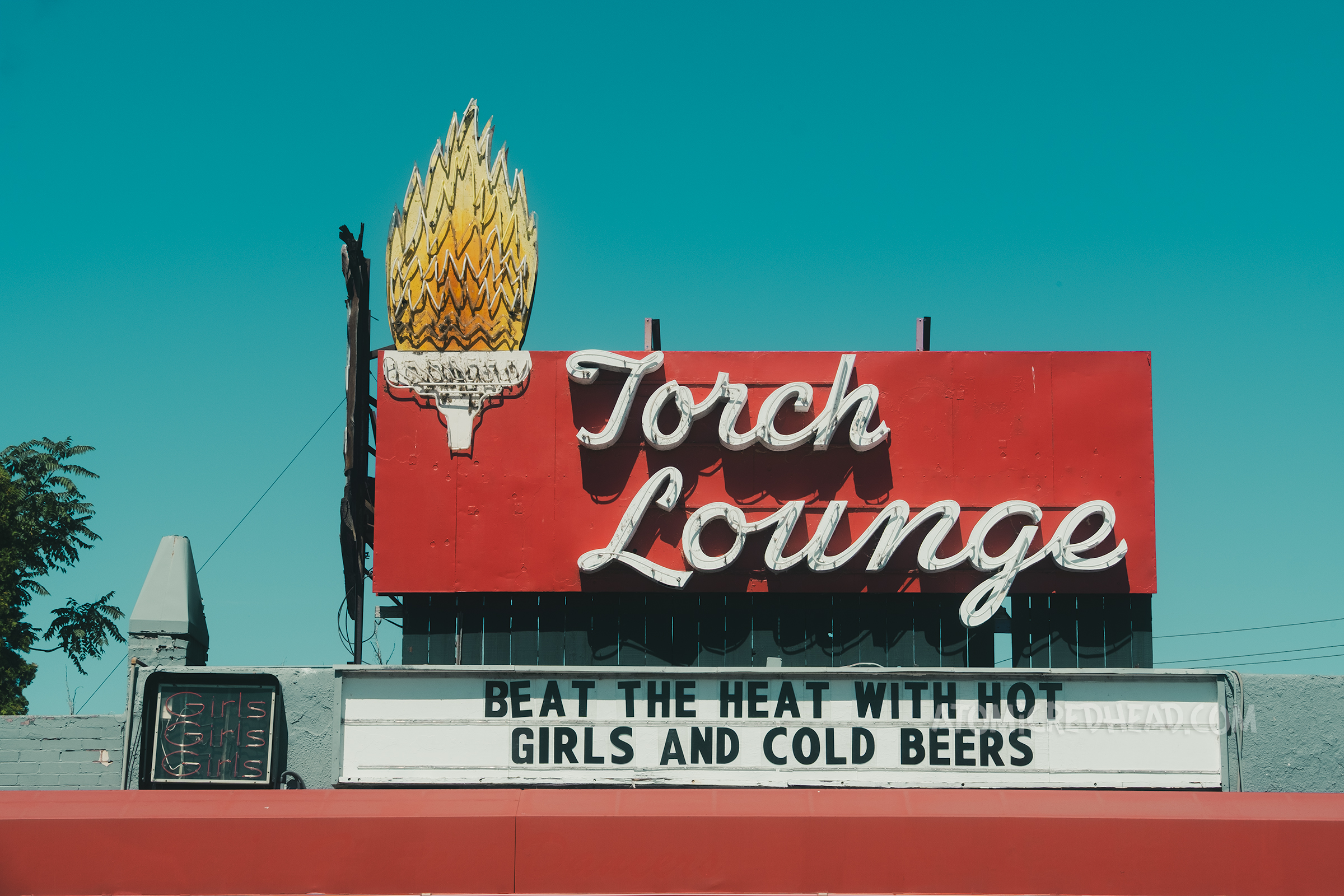 A large red and white sign reads "Torch Lounge" in white script, on the left is a neon flaming torch.