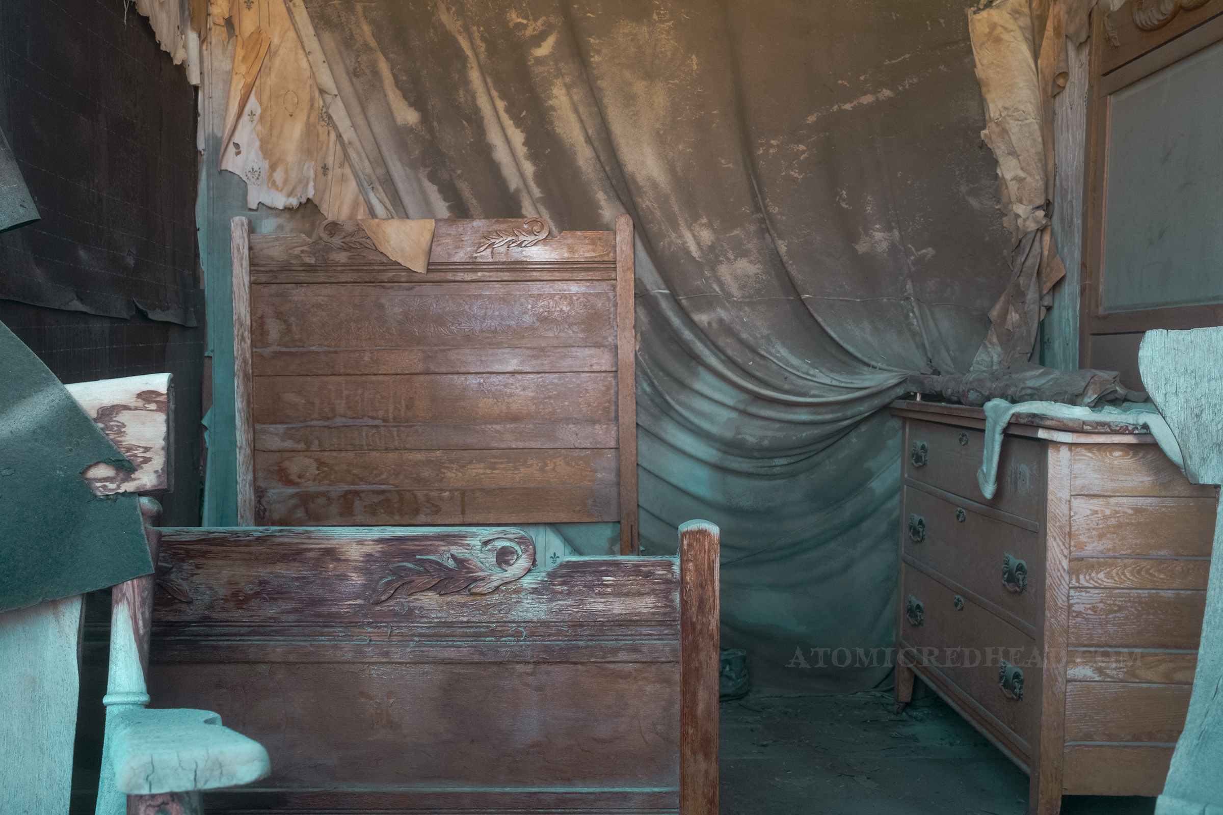 The bedroom of the old morgue, with a wooden bed and falling wallpaper.