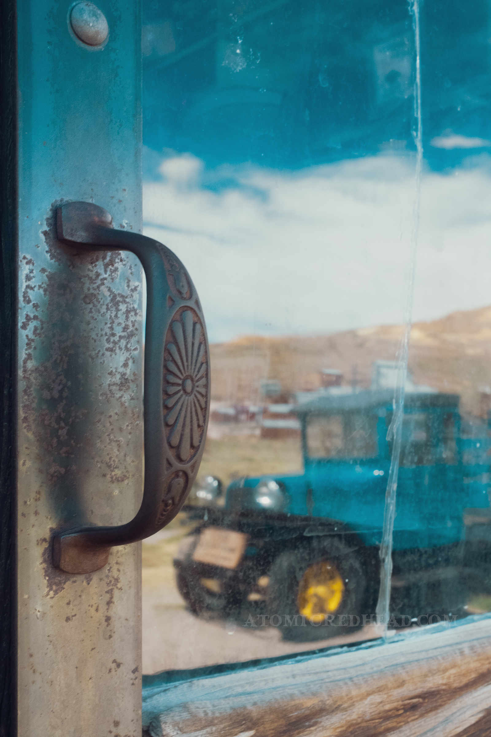 The reflection of an old blue pick-up truck in the window of the old Boone Store and Warehouse.
