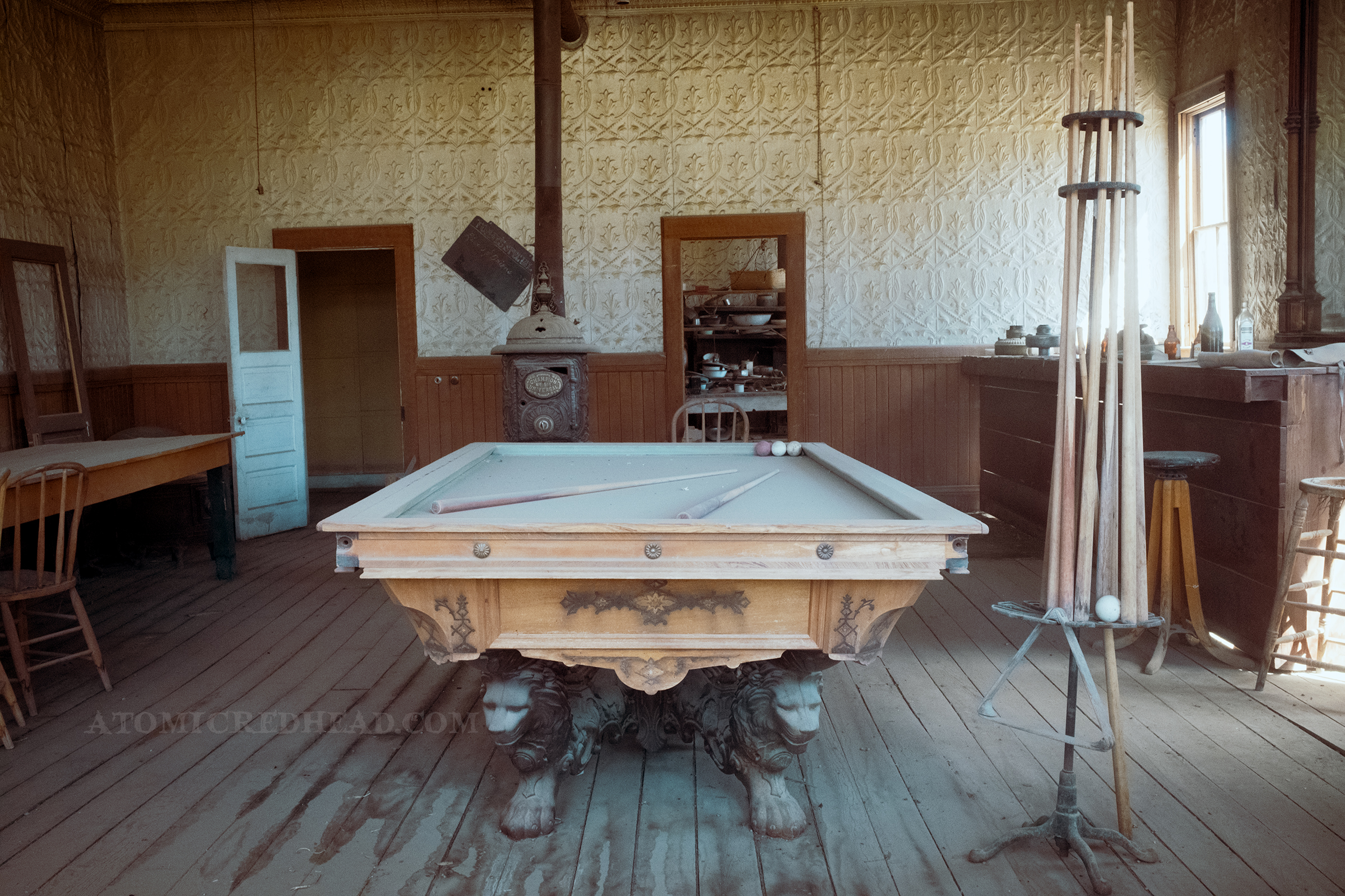 Inside an old pool hall with a large pool table with carved lions as the legs.