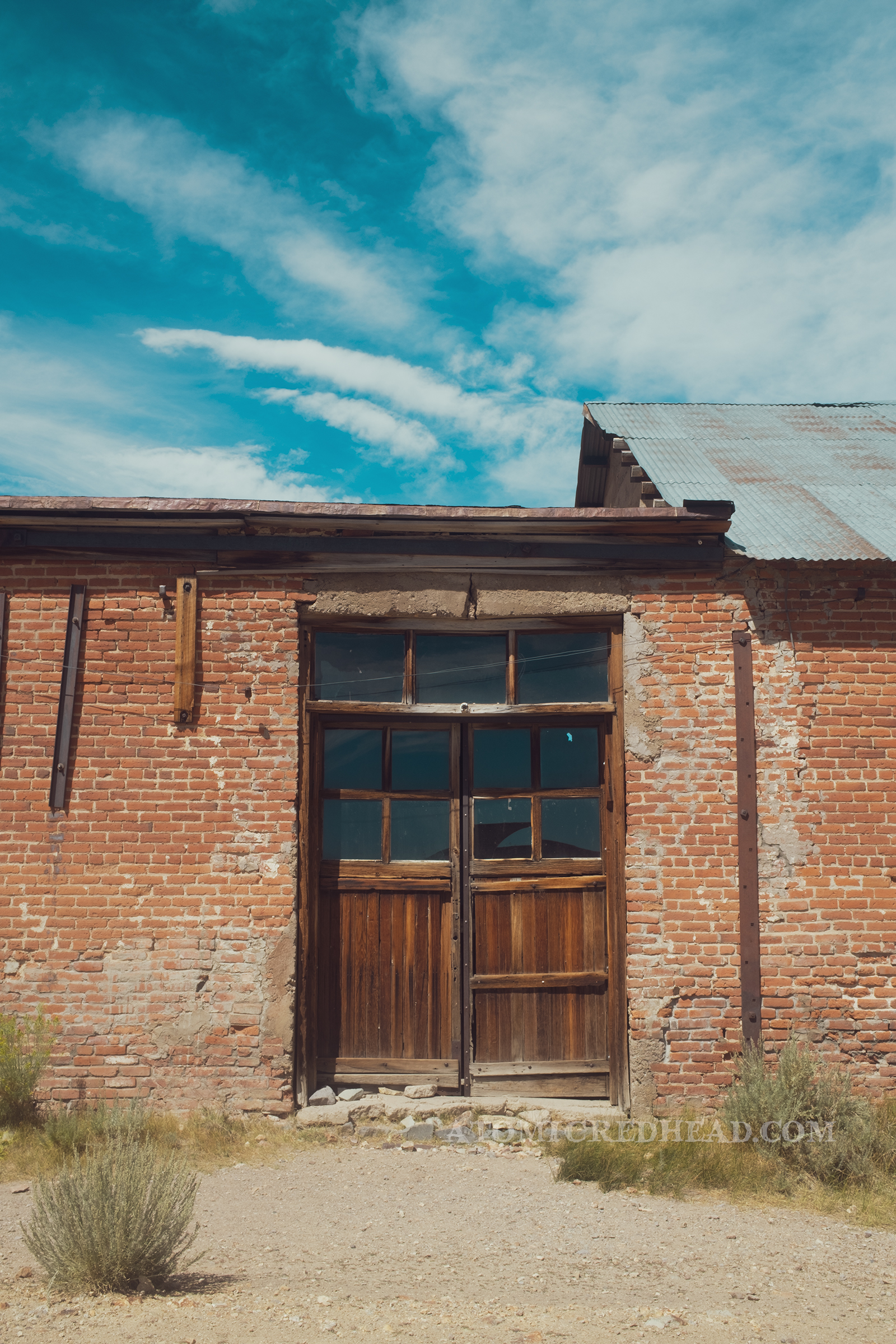 A brick building with a set of double wooden doors with windows in them.