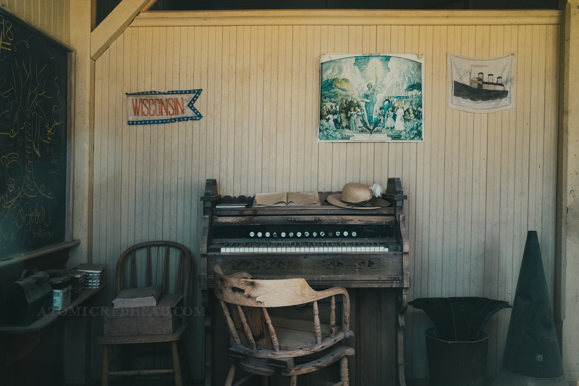 Inside the old schoolhouse, an organ sits against a cream colored wall.