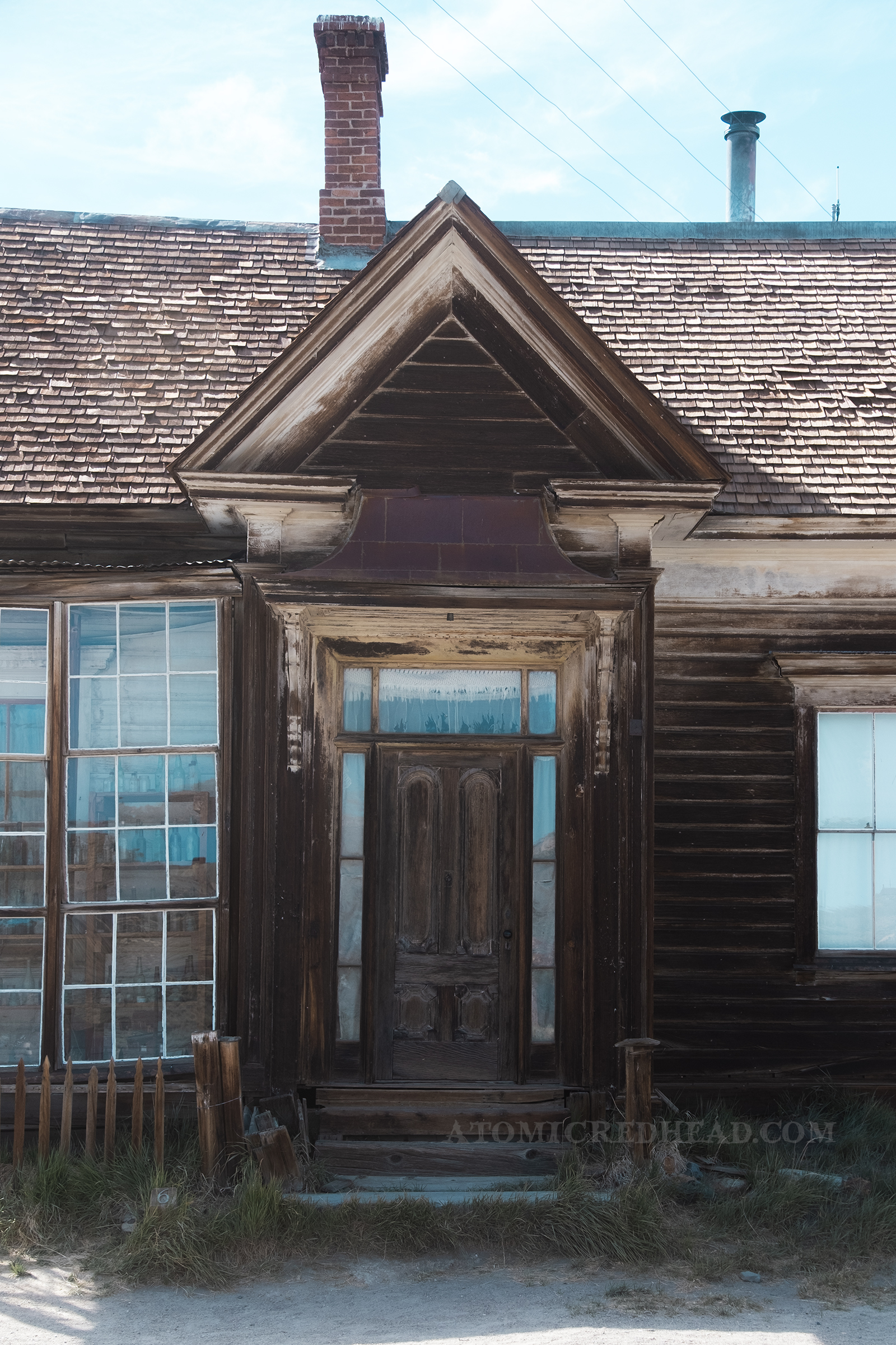 A peek roof hangs over the front door of an old house.