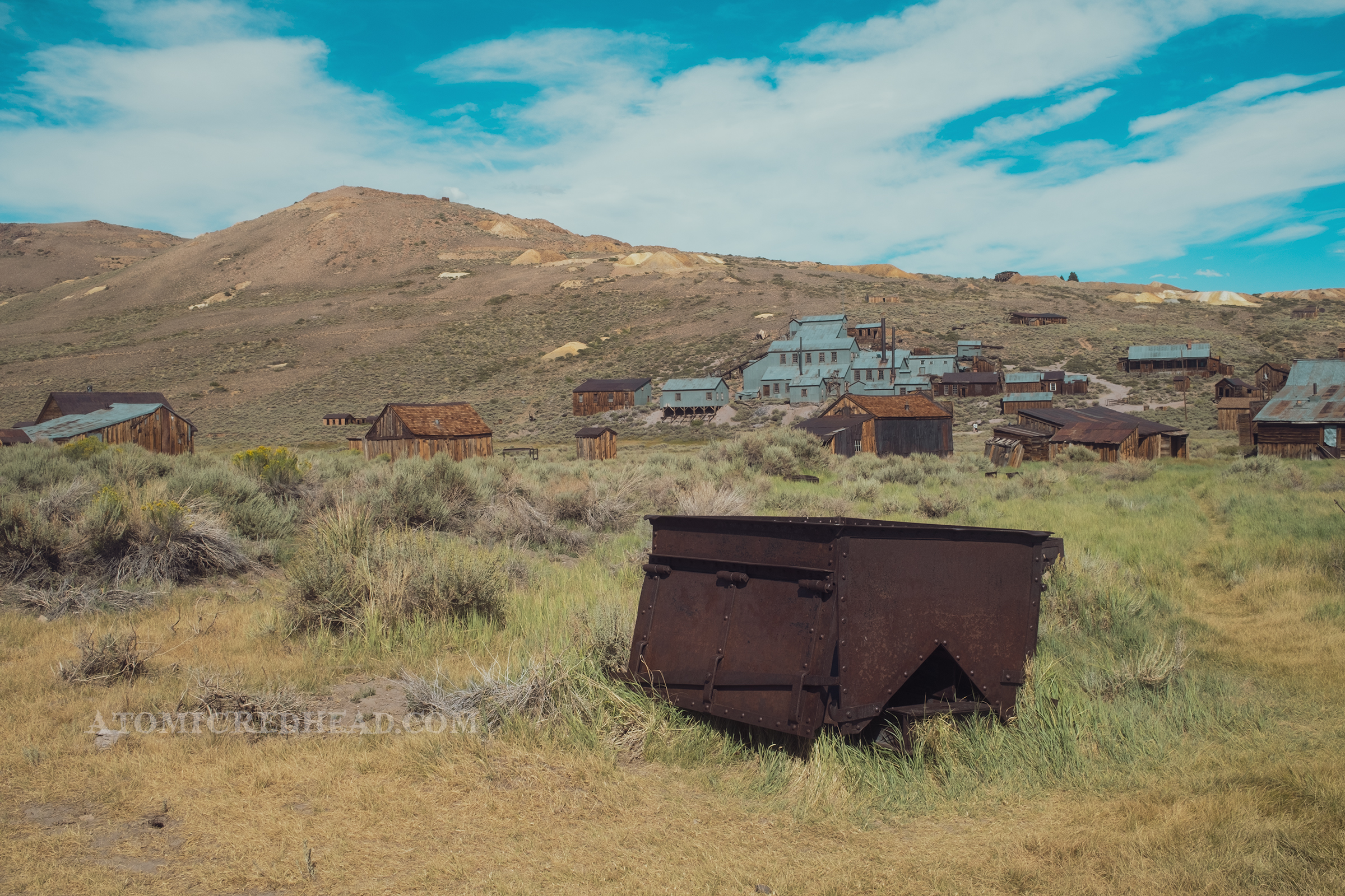 An old mine cart sits in a grassy field.
