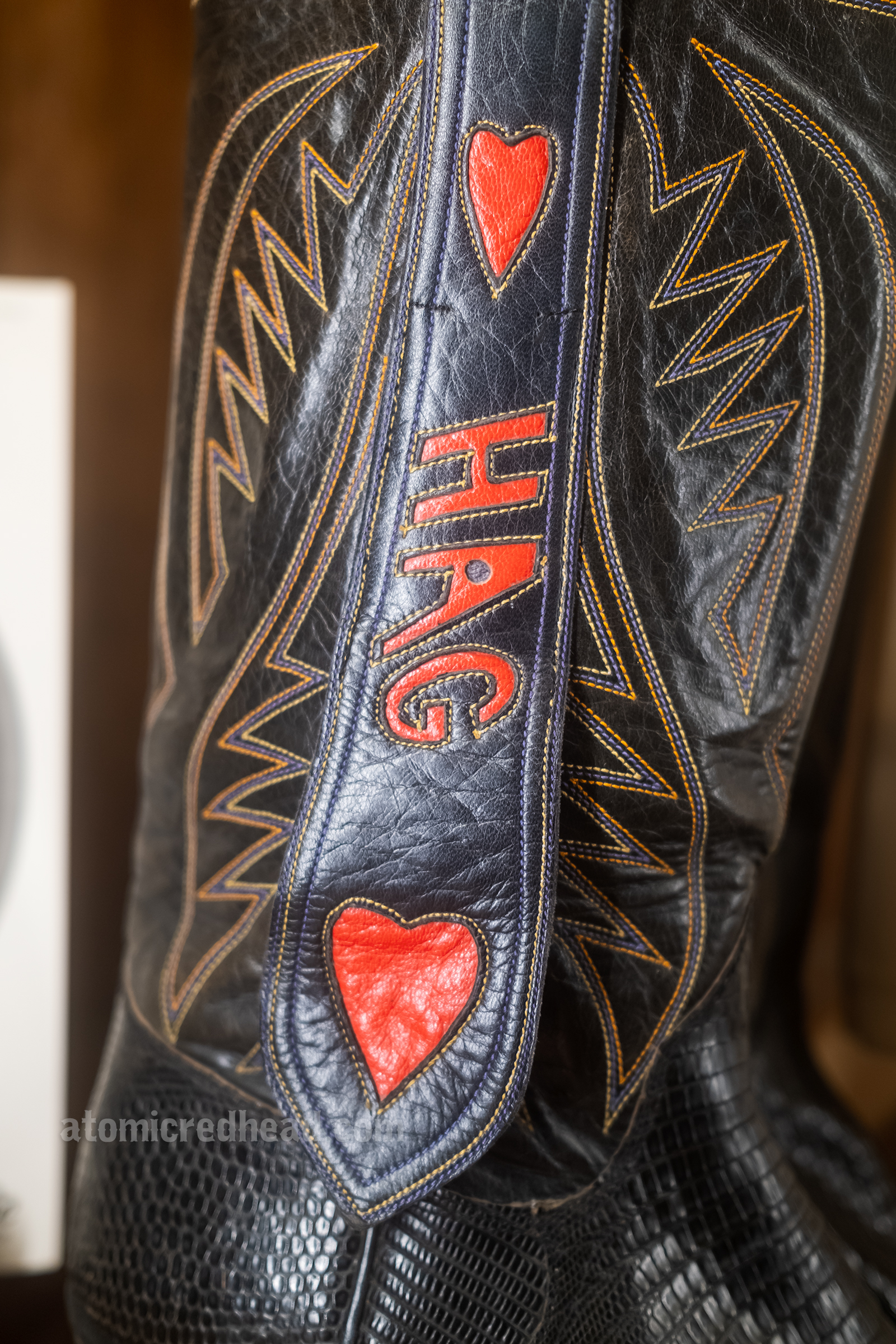 Custom cowboy boots by Nudie for Merle Haggard, black with red trim that reads "Hag" with hearts.