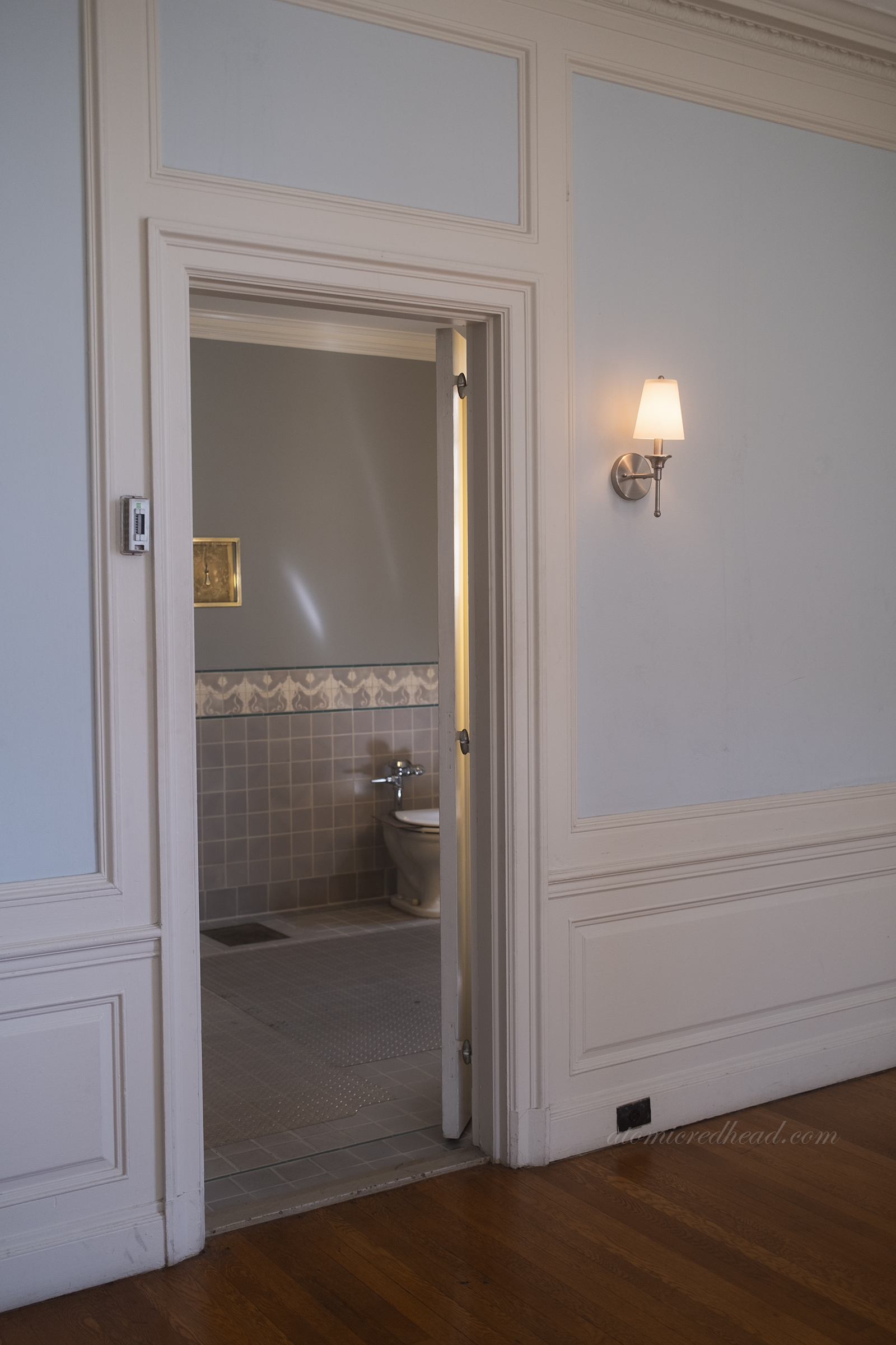 A pale blue bedroom with white trim, with a doorway leading into the bathroom.
