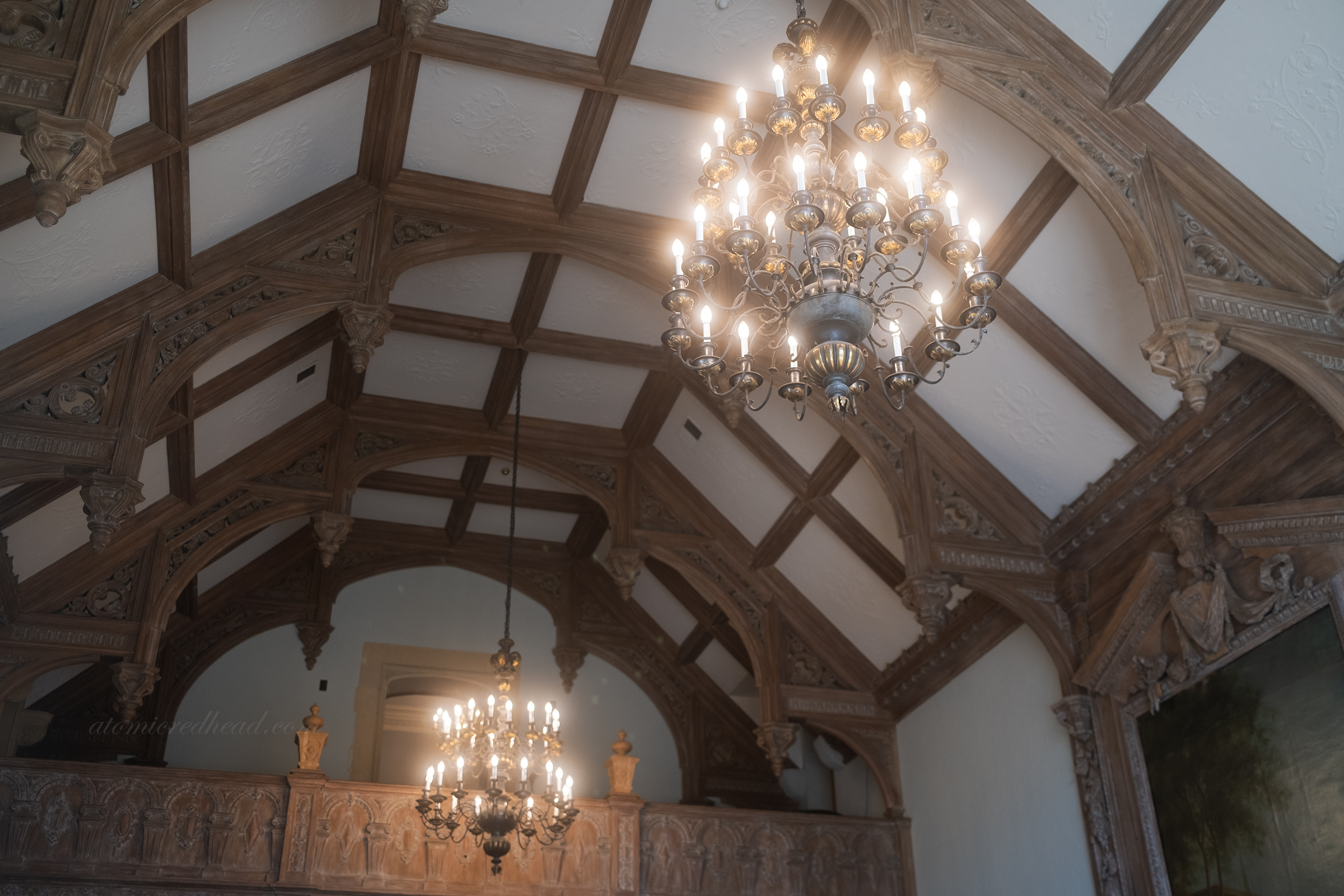 Two massive chandeliers hang in the arched living room, with minstrel gallery above.