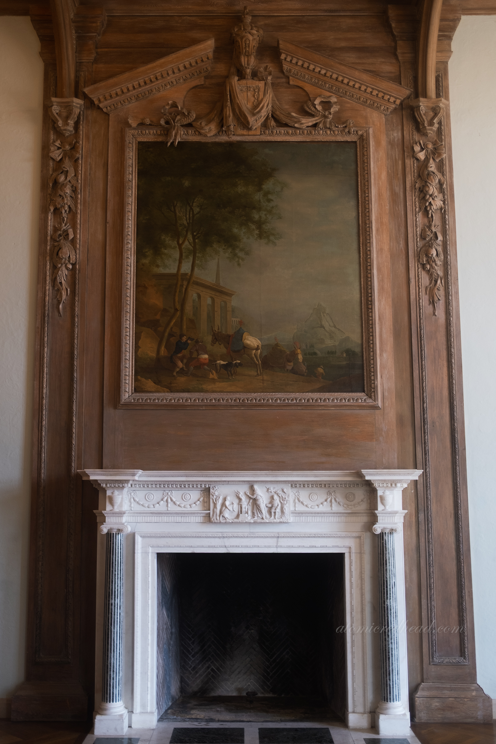 A large landscape painting above the fireplace, made of white marble, in the living room.